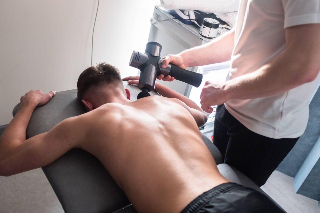 A man is laying on a table getting a massage from another man.