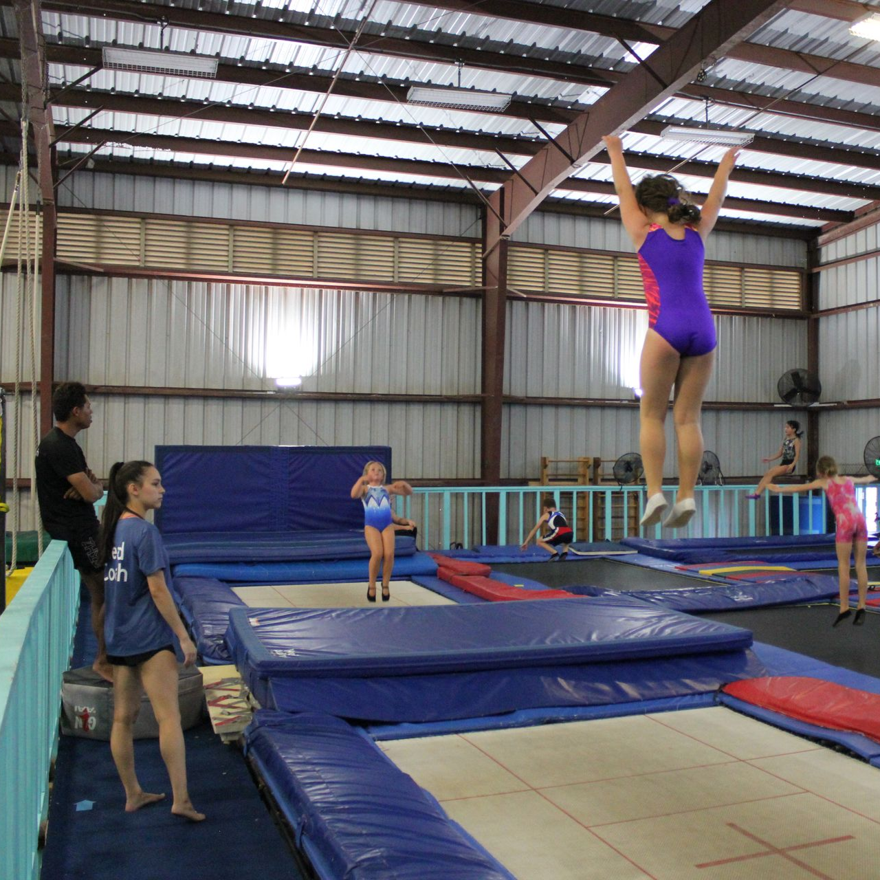 A gymnast is sitting on a balance beam covered in chalk.