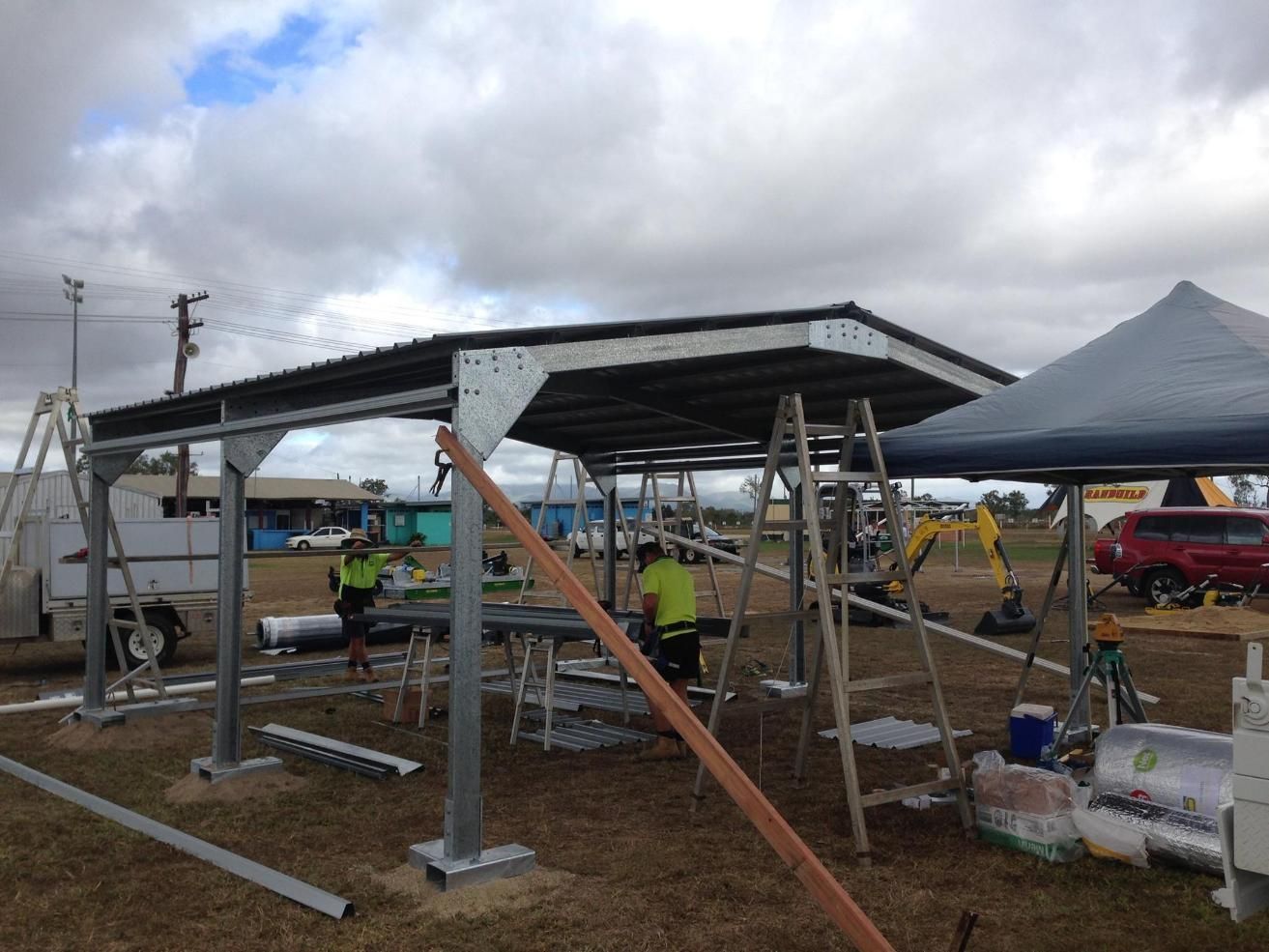 A Group Of People Are Working On A Structure In A Field — Dunnrite Mareeba Sheds & Garages In Mareeba, QLD