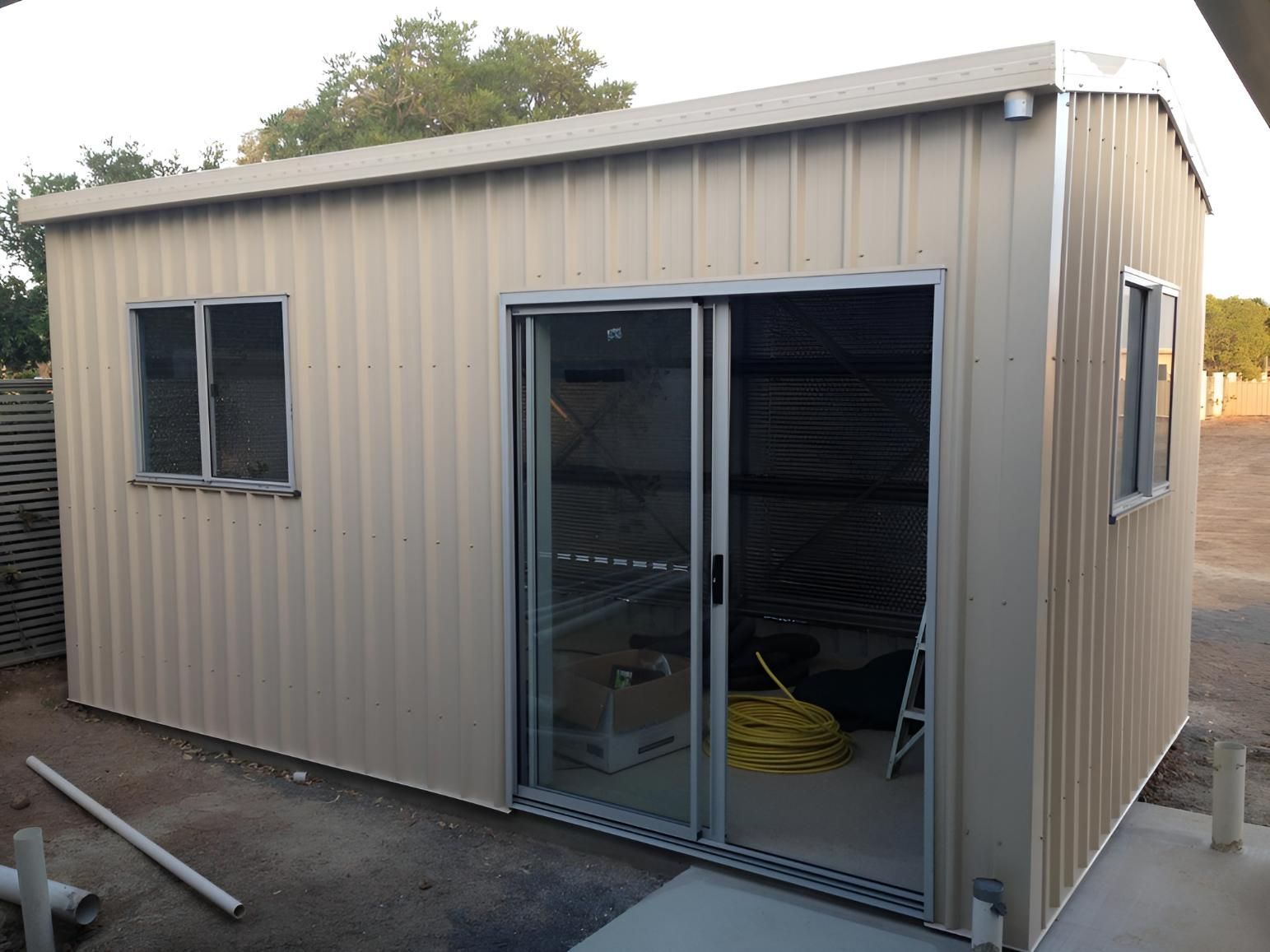 A Small Metal Building With A Sliding Glass Door And Two Windows — Dunnrite Mareeba Sheds & Garages In Atherton, QLD