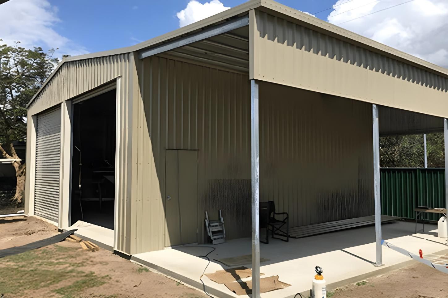 A Large Metal Building With A Canopy And A Chair In Front Of It — Dunnrite Mareeba Sheds & Garages In Mareeba, QLD