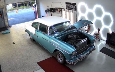 Turquoise classic car in a garage with hood open and front end exposed