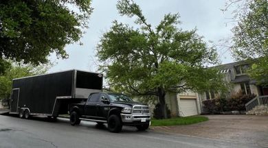 A truck with a trailer attached to it is parked in front of a house.