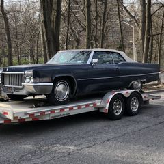 A black car is sitting on top of a trailer.
