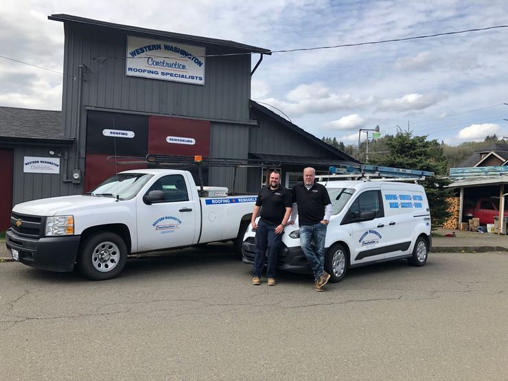 Western Washington Construction owners standing beside company vehicles outside the office