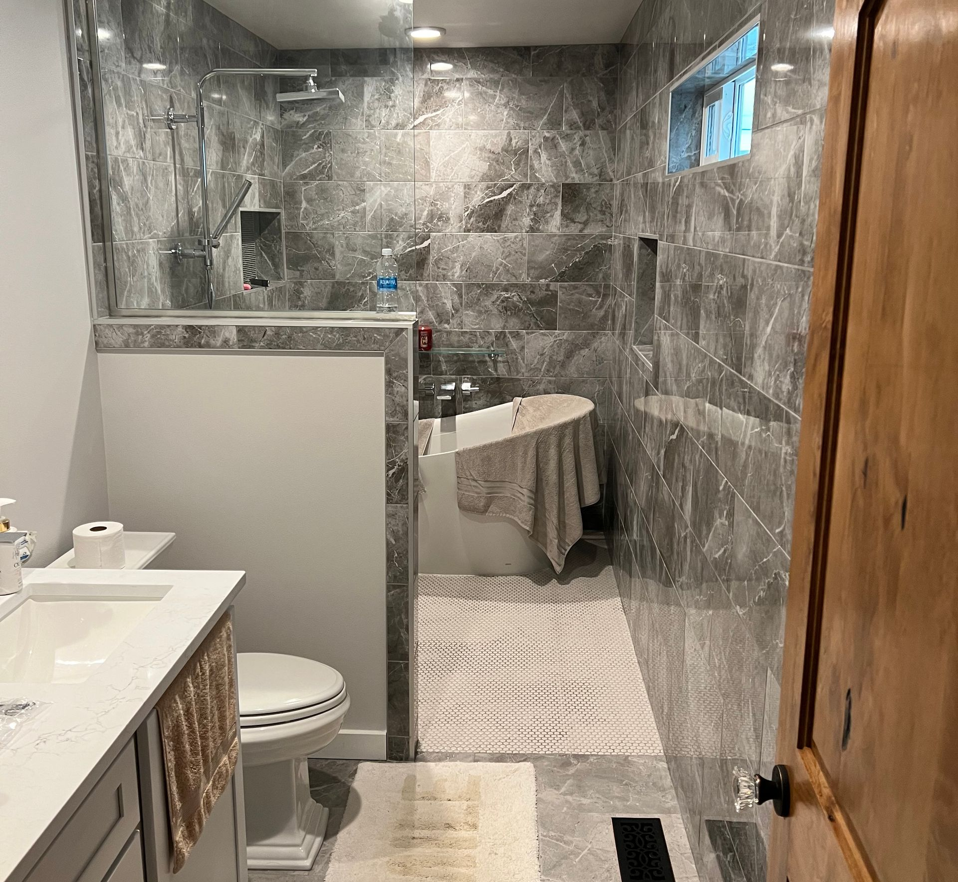 Remodeled bathroom with gray tile walls and a glass shower partition