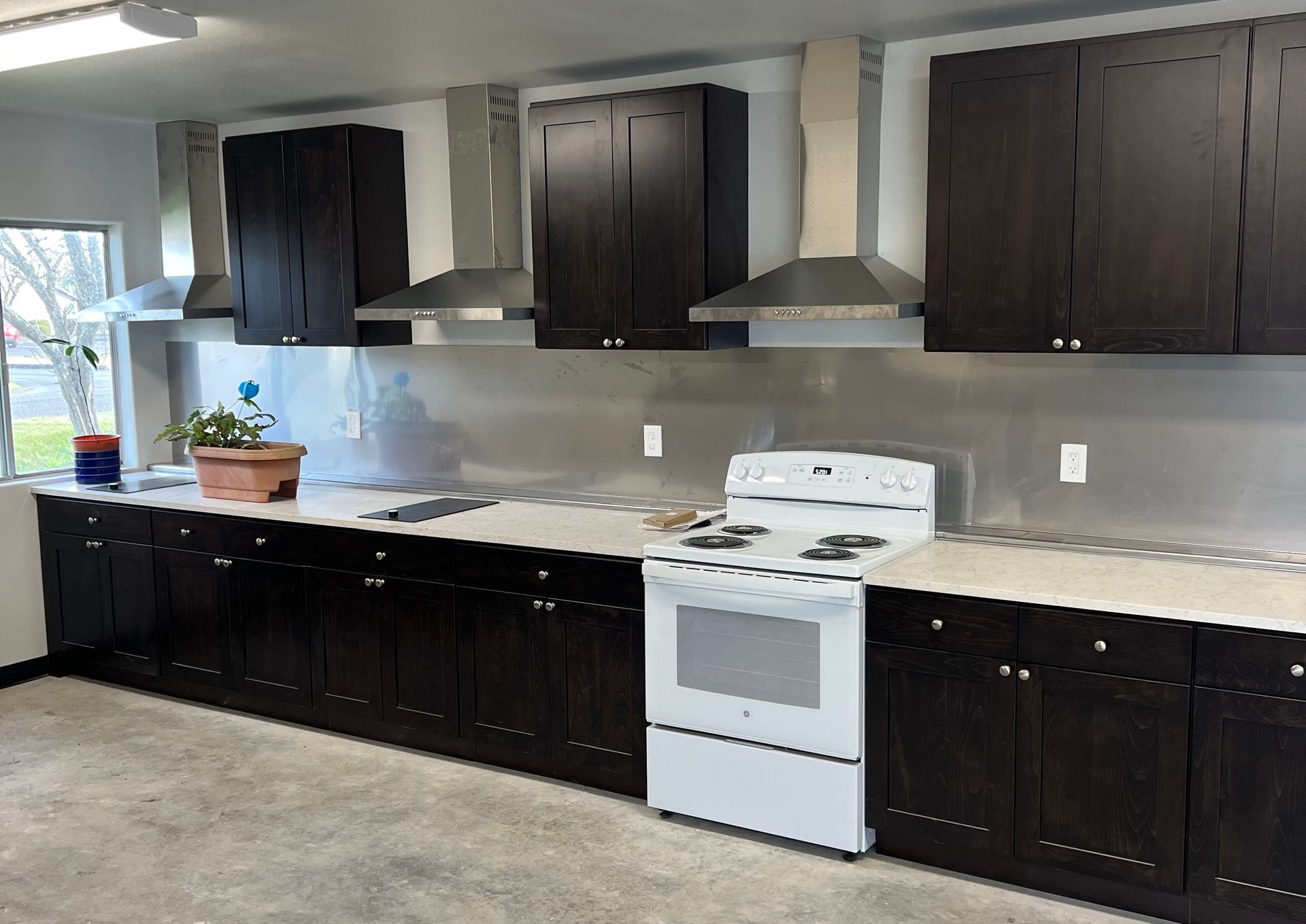 Remodeled kitchen with dark wood cabinets, light countertops, and a stainless steel range hood