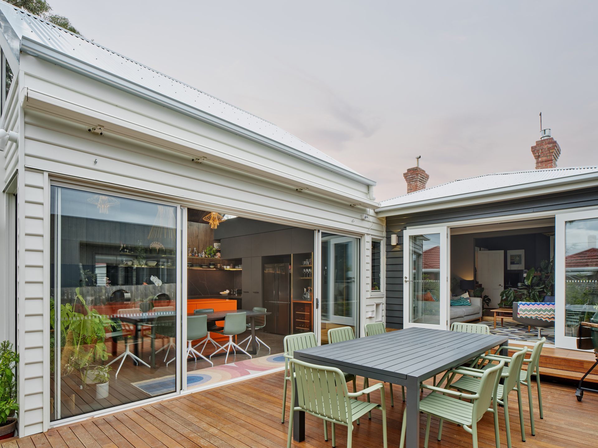 There is a table and chairs on the deck of a house.