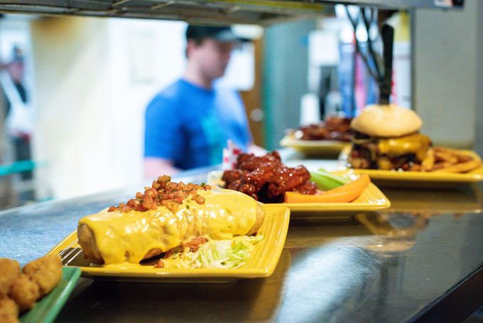 A man is standing behind a counter with plates of food on it.