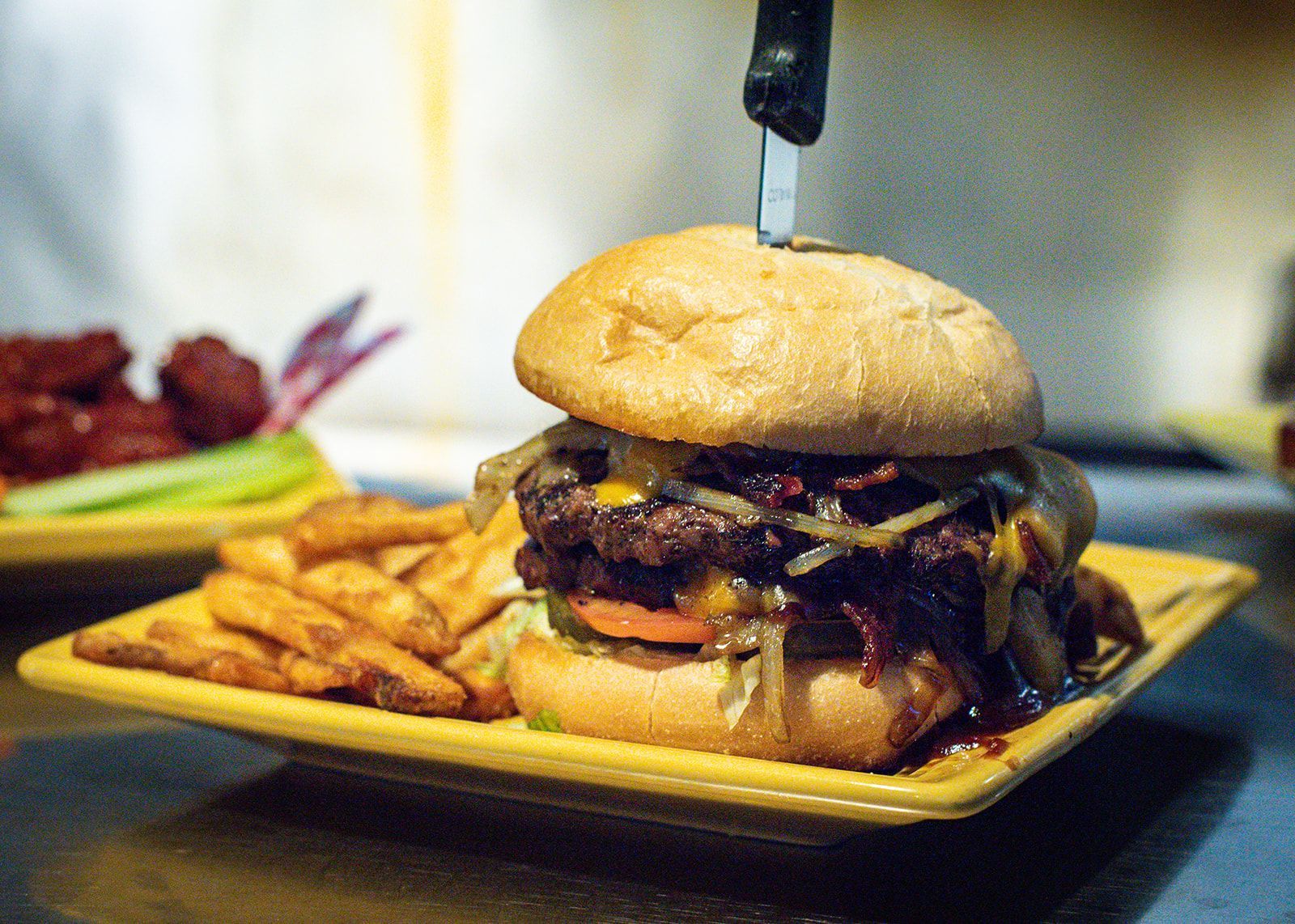 A hamburger and french fries on a yellow plate on a table.