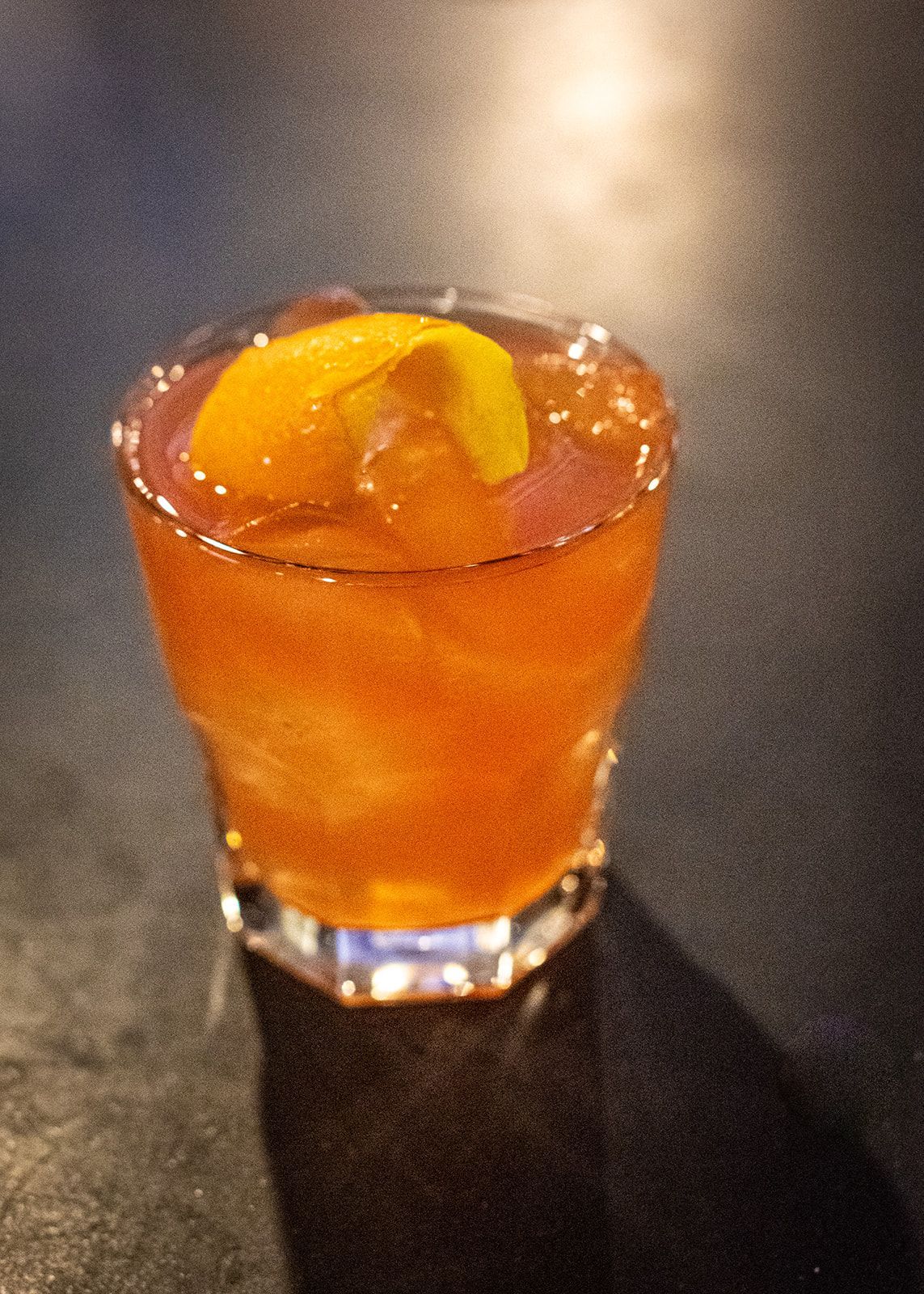 A glass of orange liquid with a lemon slice on top