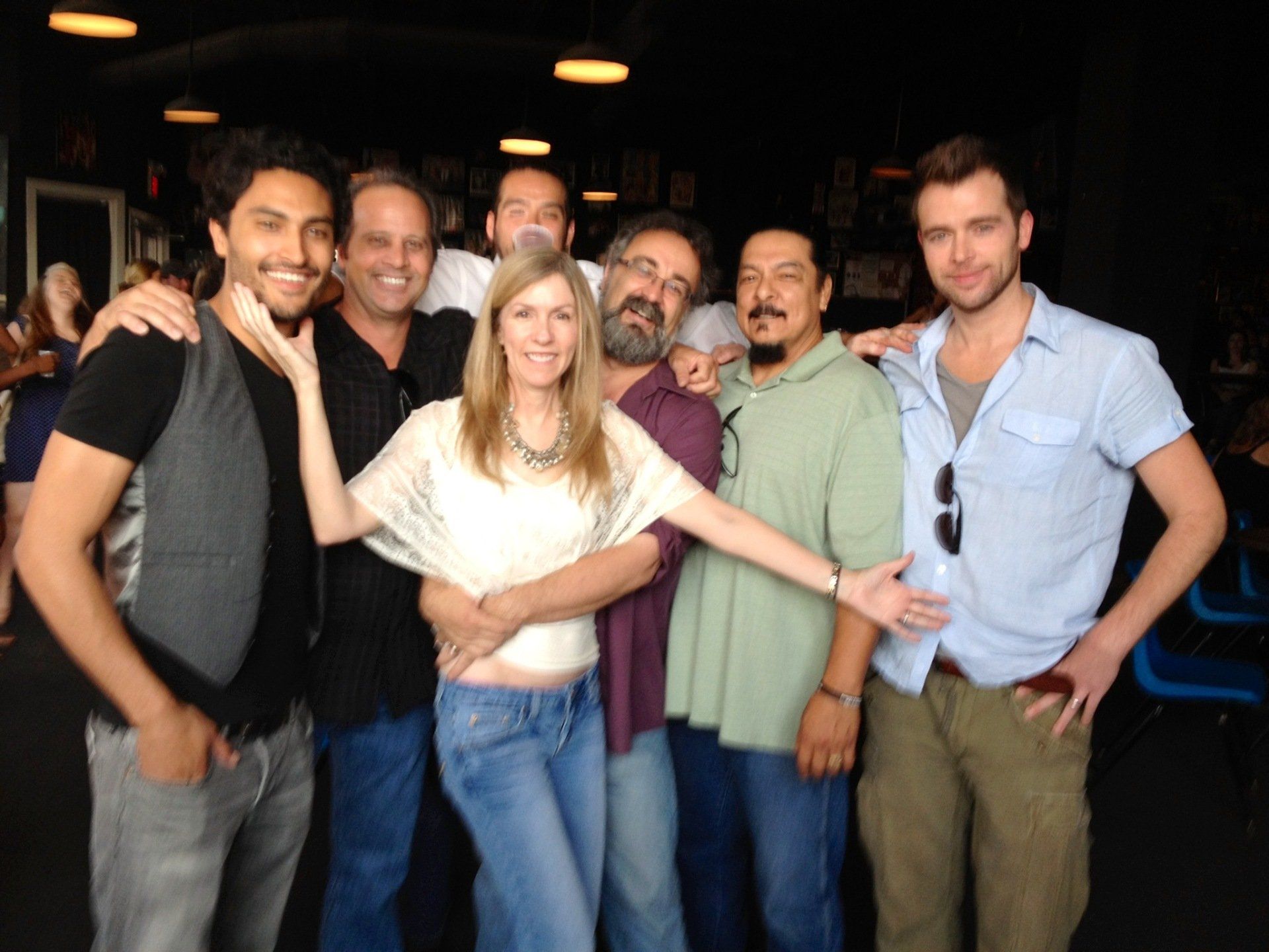A group of seven people pose for a photo in an indoor setting with overhead lighting, smiling and standing together.