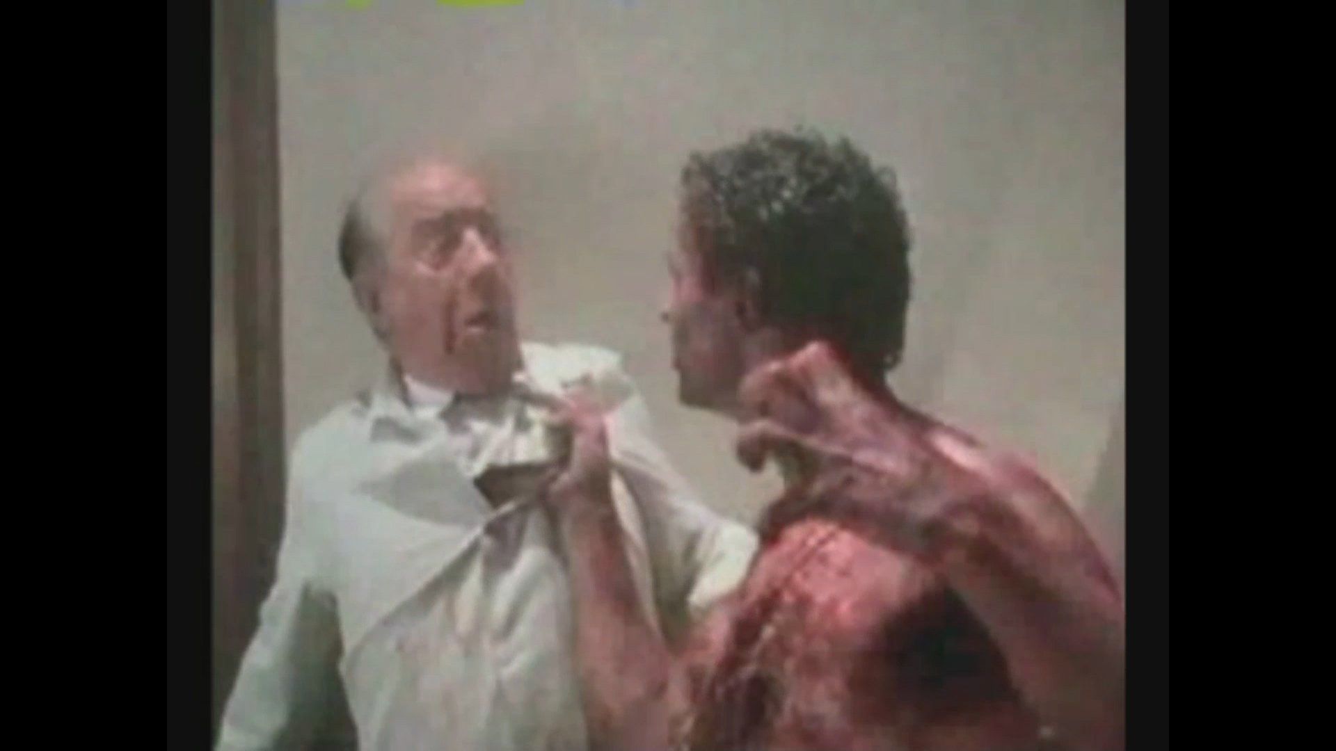 A bloodied, claw-handed figure grabs the shirt collar of a person in a white button-down shirt.