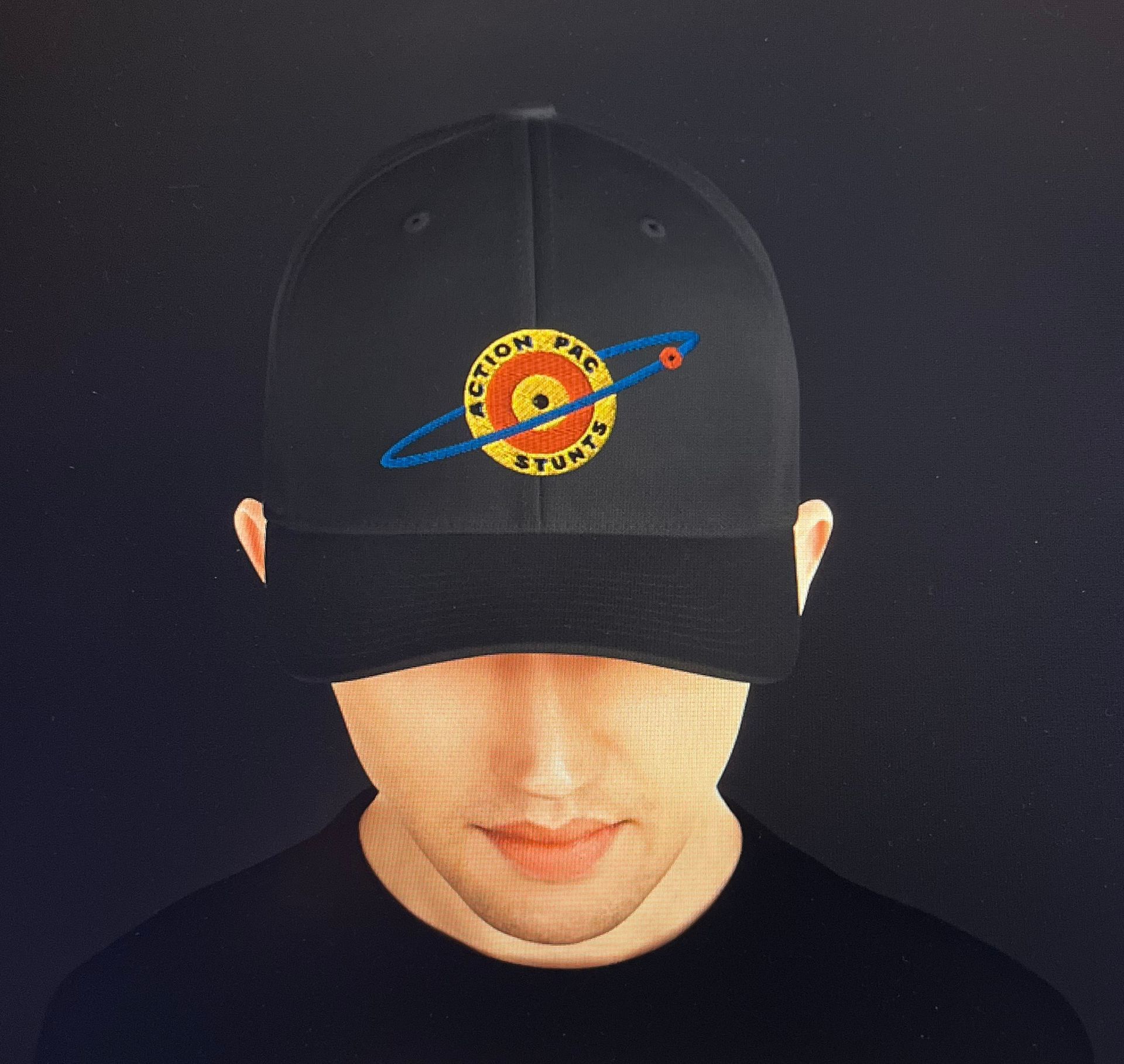 A person wearing a black baseball cap featuring an embroidered logo of a planet with a ring and the text 