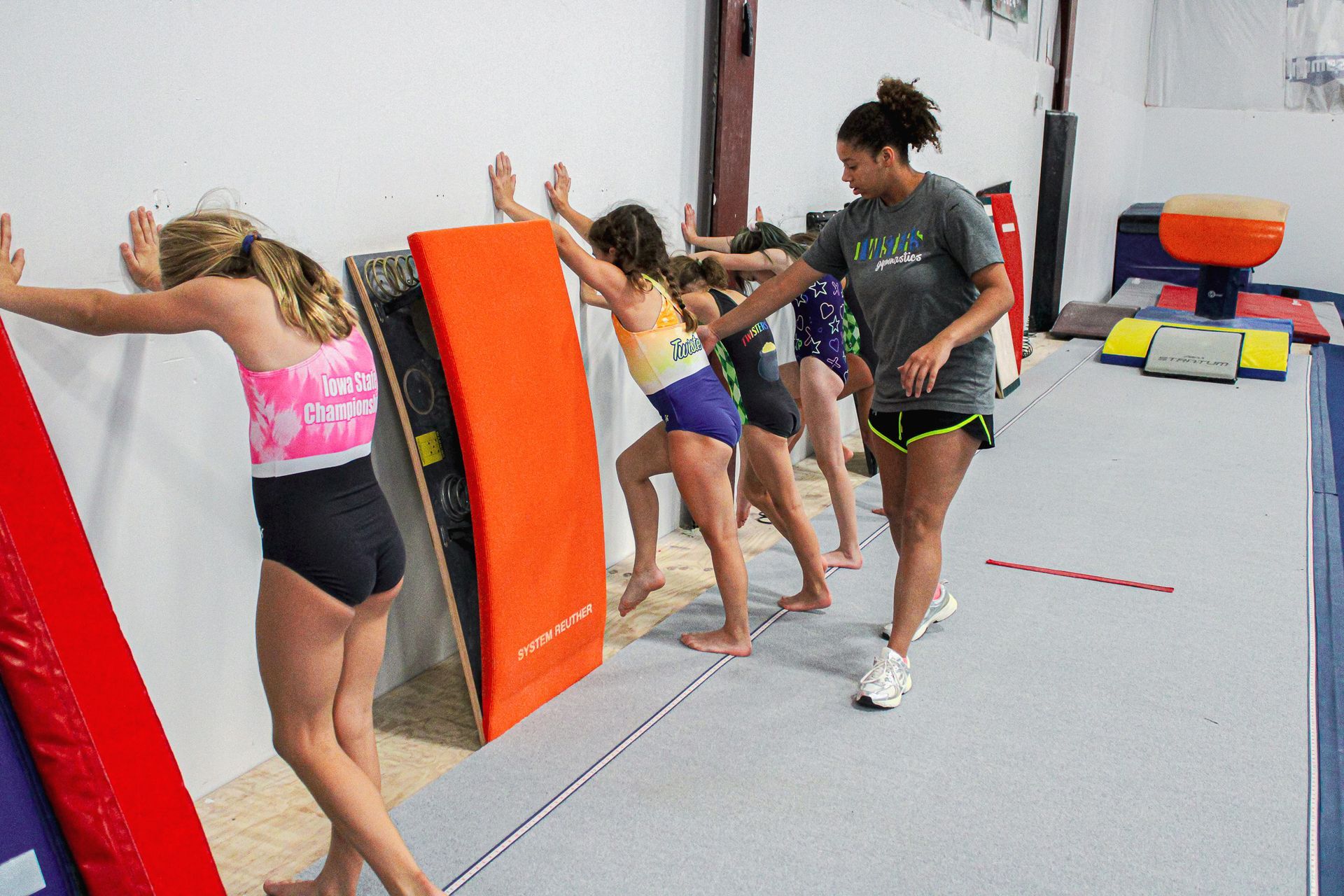 People climbing over orange padded mats in an indoor gym obstacle course