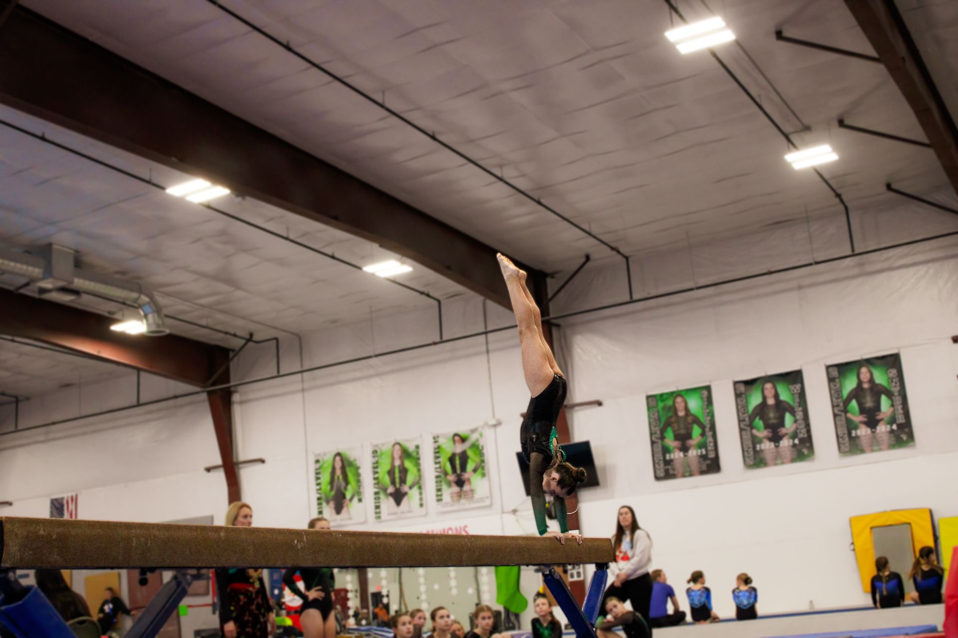 Gymnast balancing upside down on a beam in an indoor gymnasium