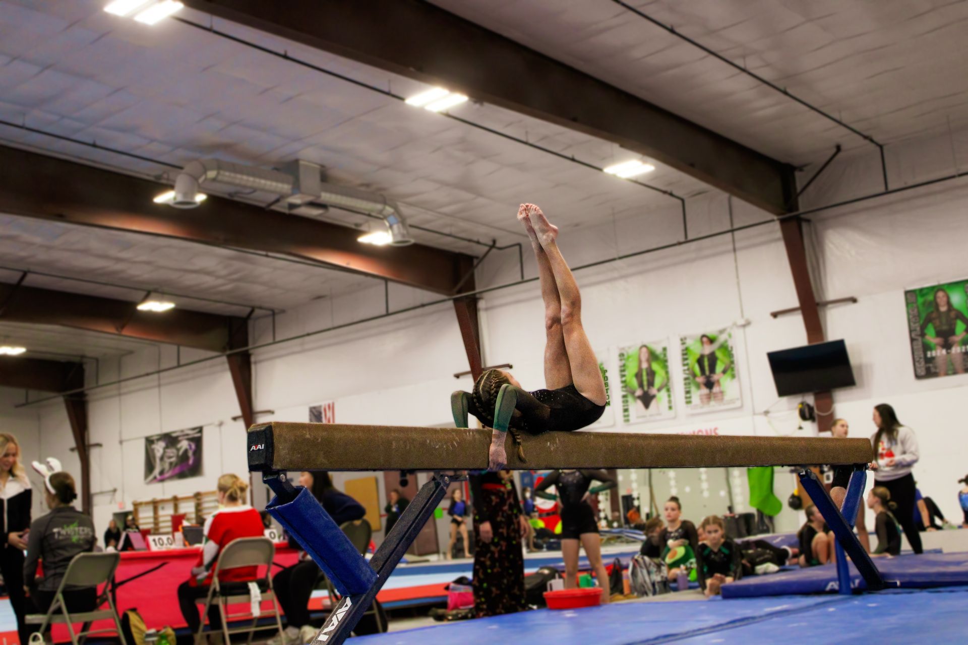 Gymnast balancing on a beam in a gym with spectators watching