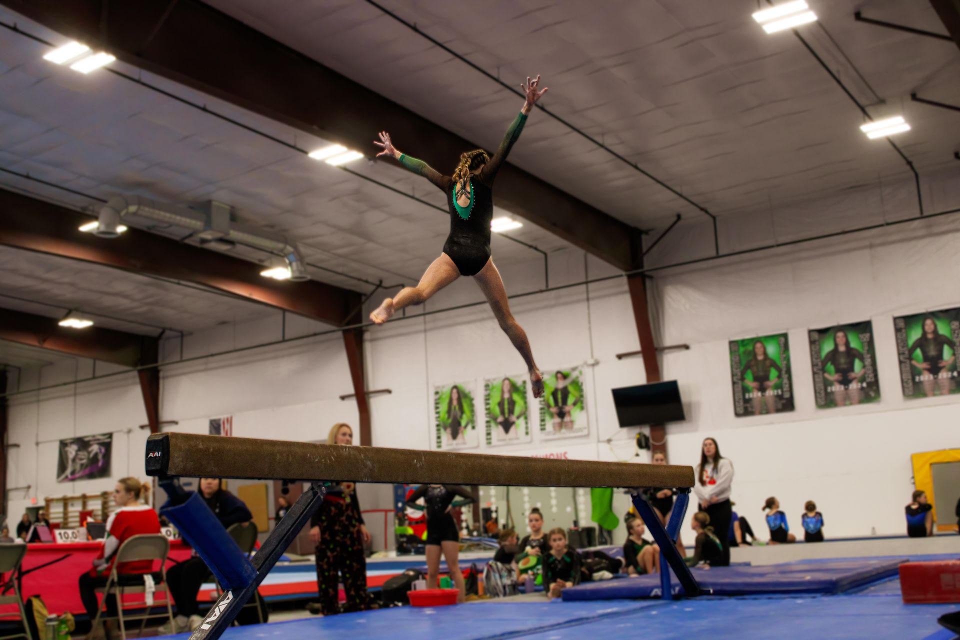 Gymnast leaping over a balance beam in an indoor gymnasium during practice.