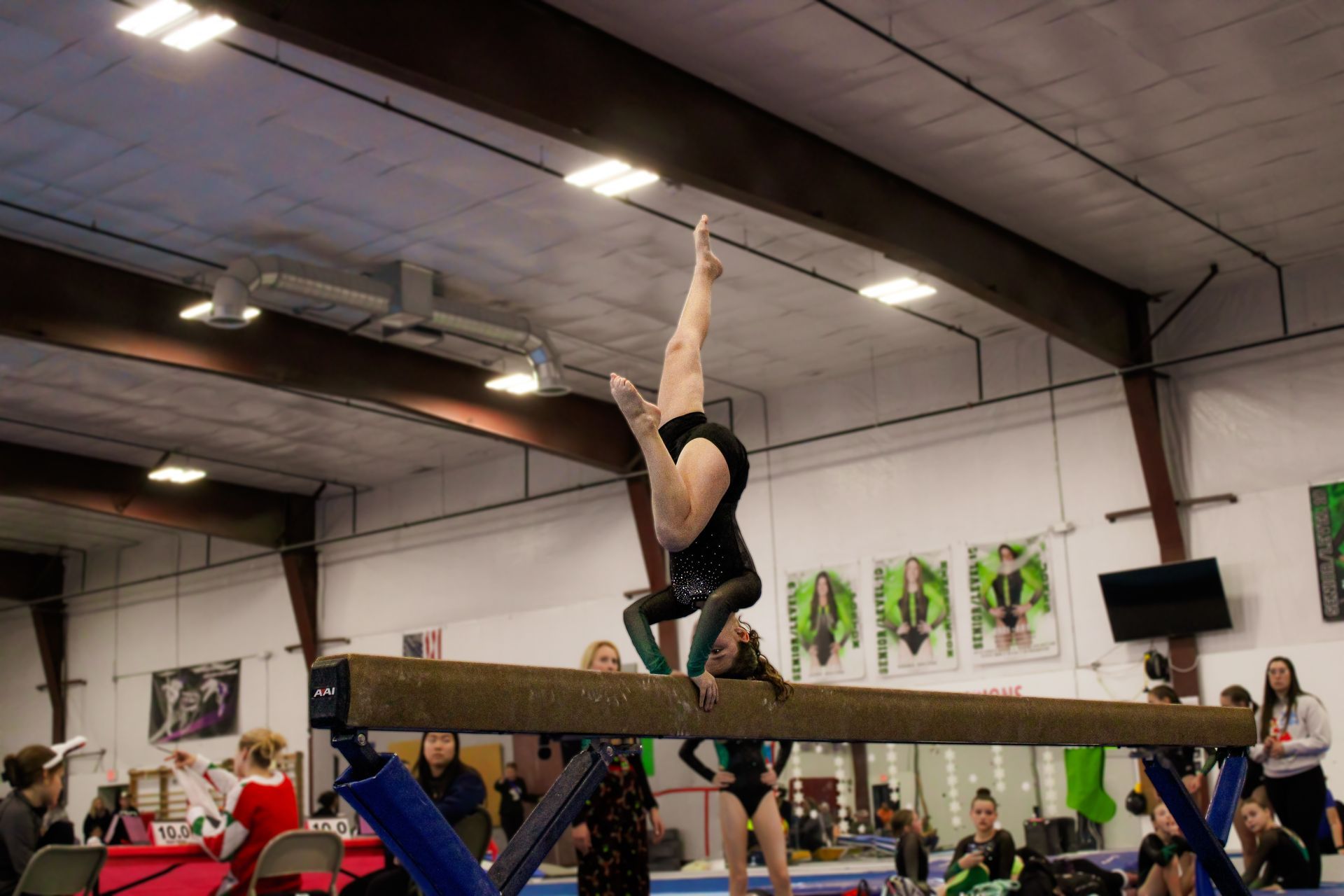 Gymnast balancing upside down on a beam in an indoor gymnasium
