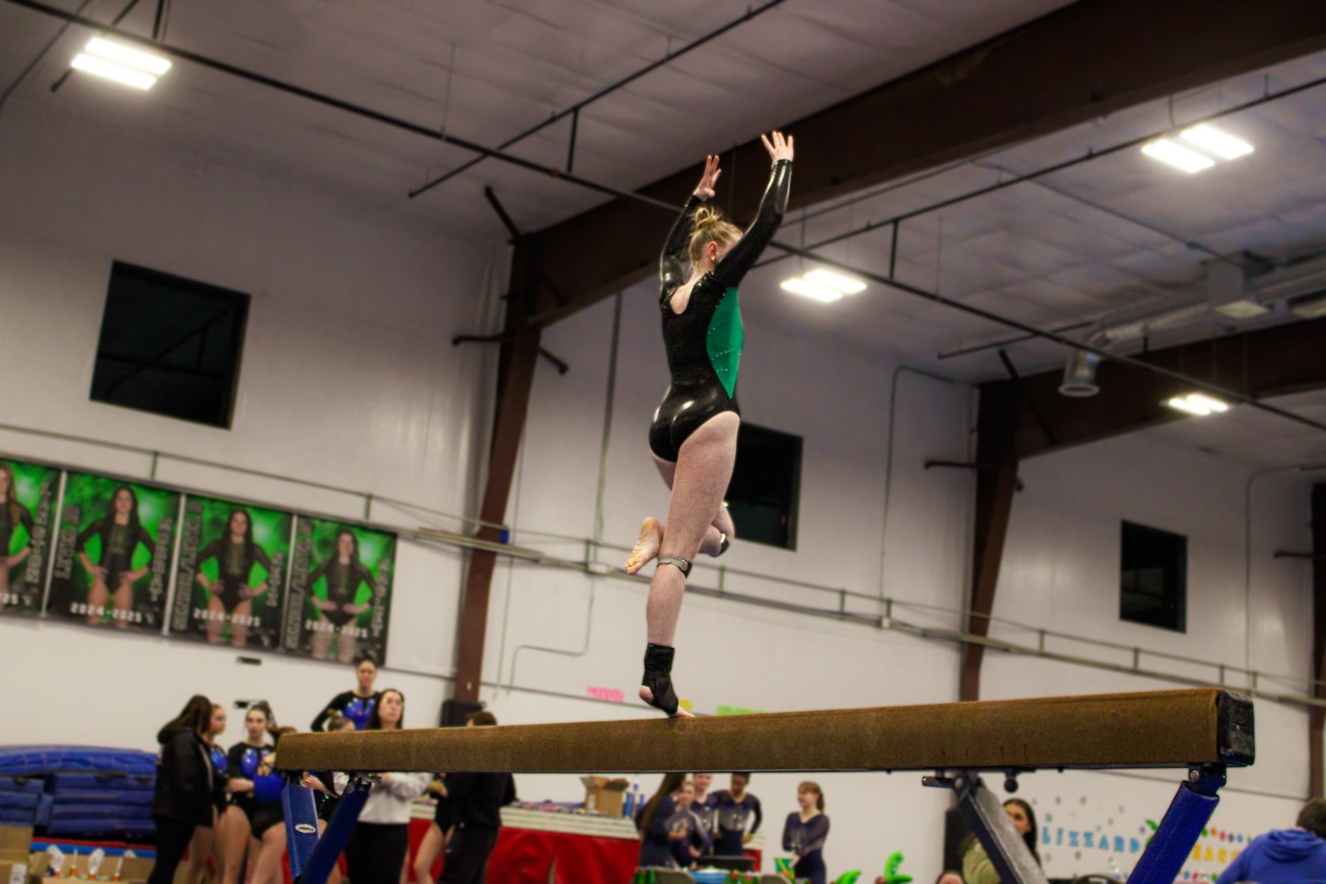 Gymnast balancing upside down on a beam in an indoor gymnasium during practice