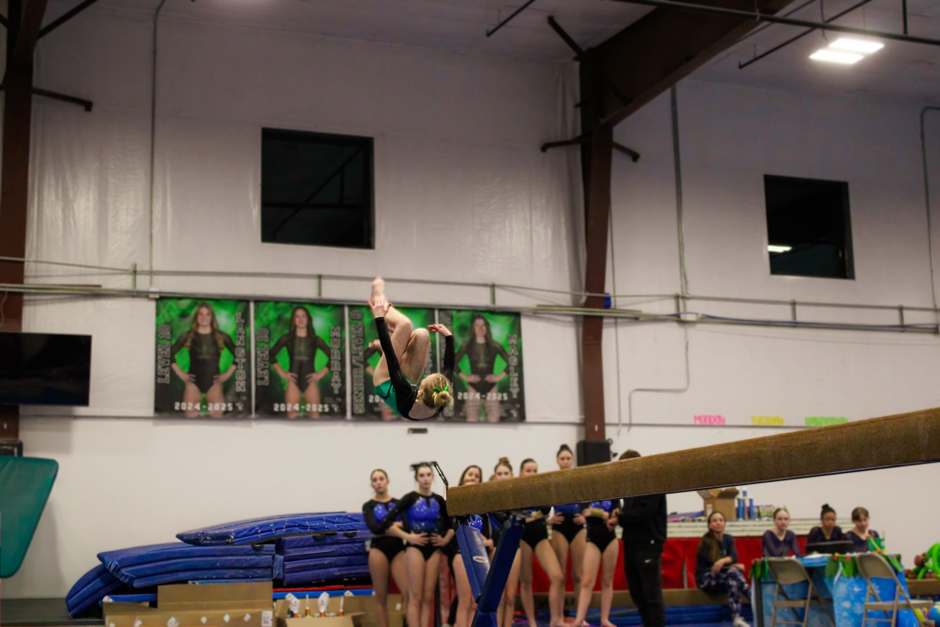 Gymnast performing a vault over a table while teammates watch in an indoor gymnasium