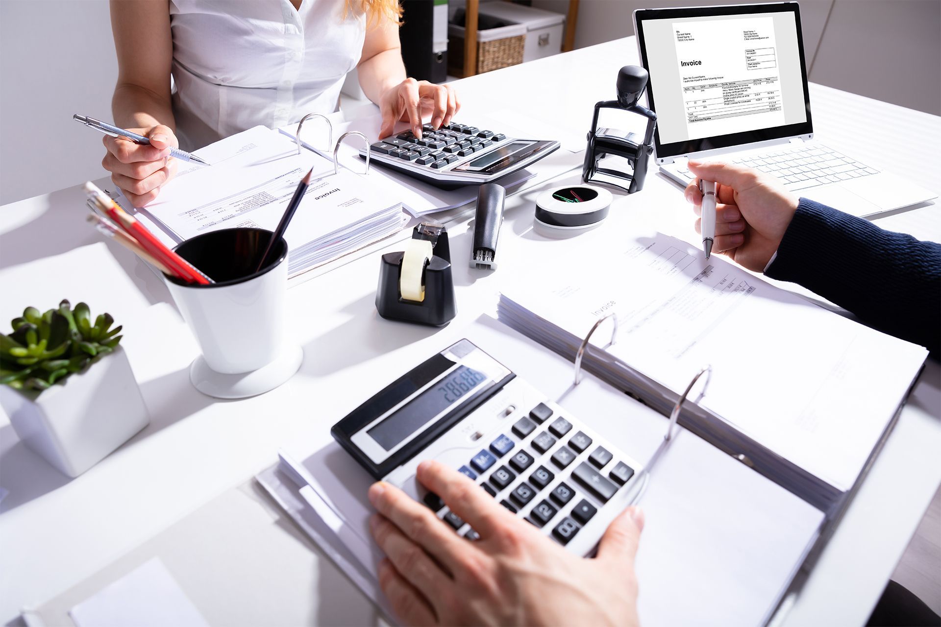 People using calculators and laptops during a team budget meeting.