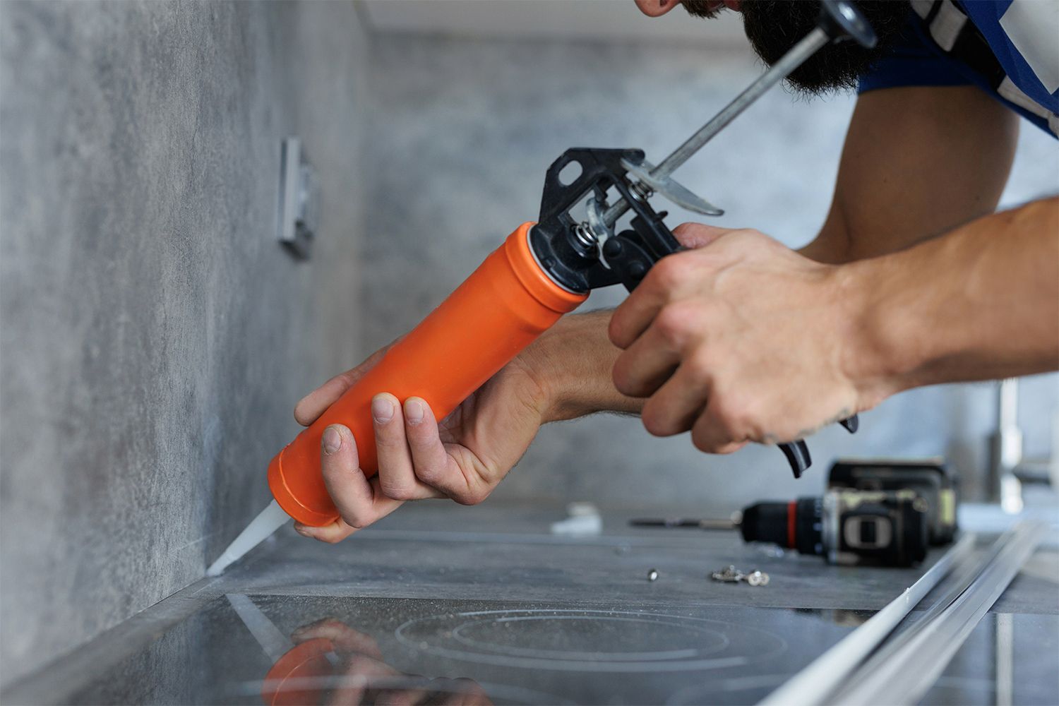 A man is applying silicone to a counter top.