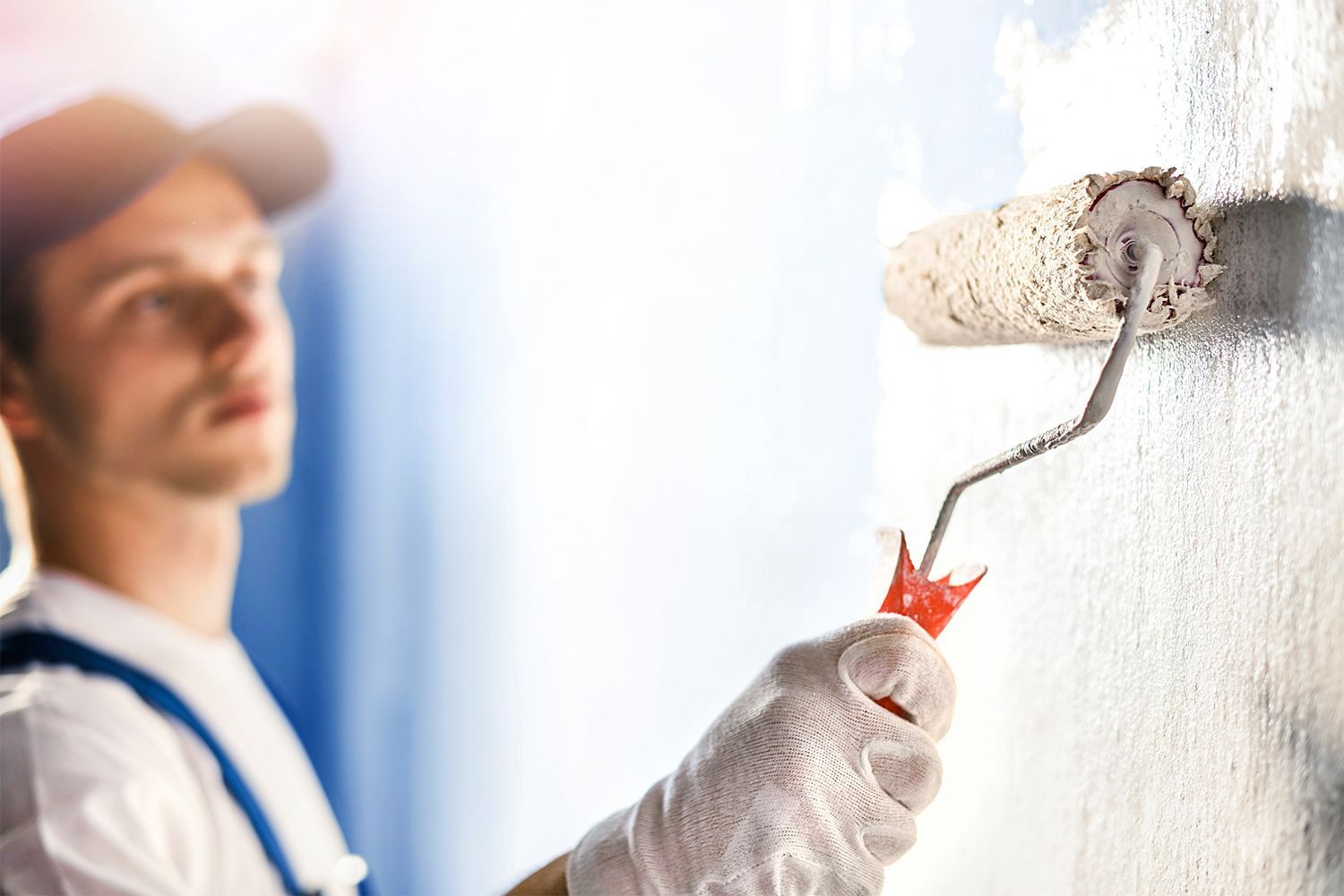 A man is painting a wall with a paint roller.