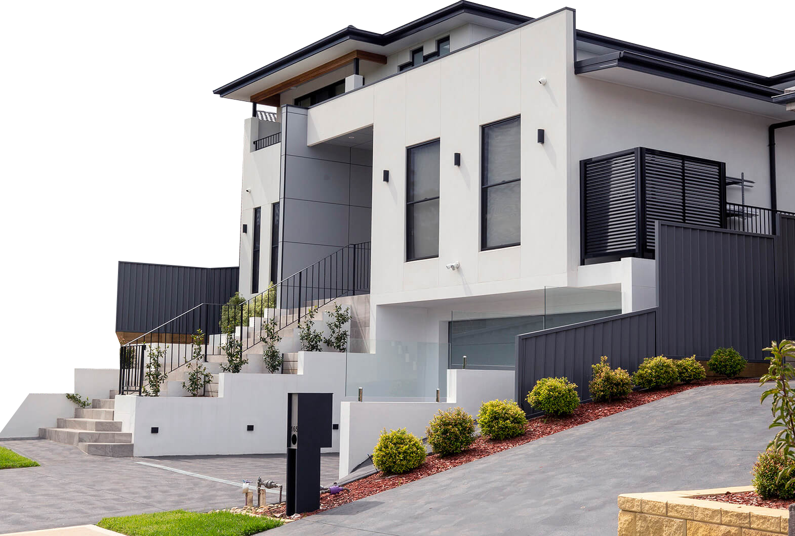 A large white house with a black fence is sitting on top of a hill.