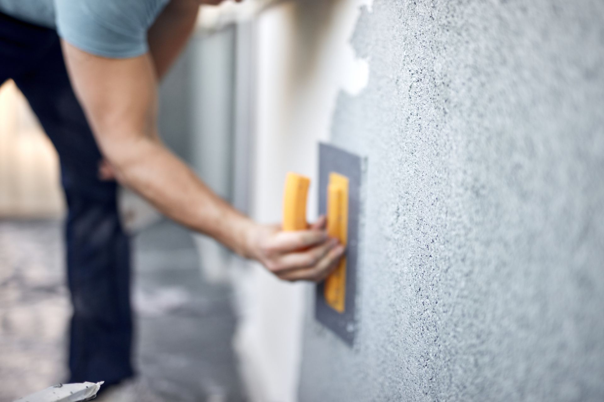 A man is plastering a wall with a trowel.