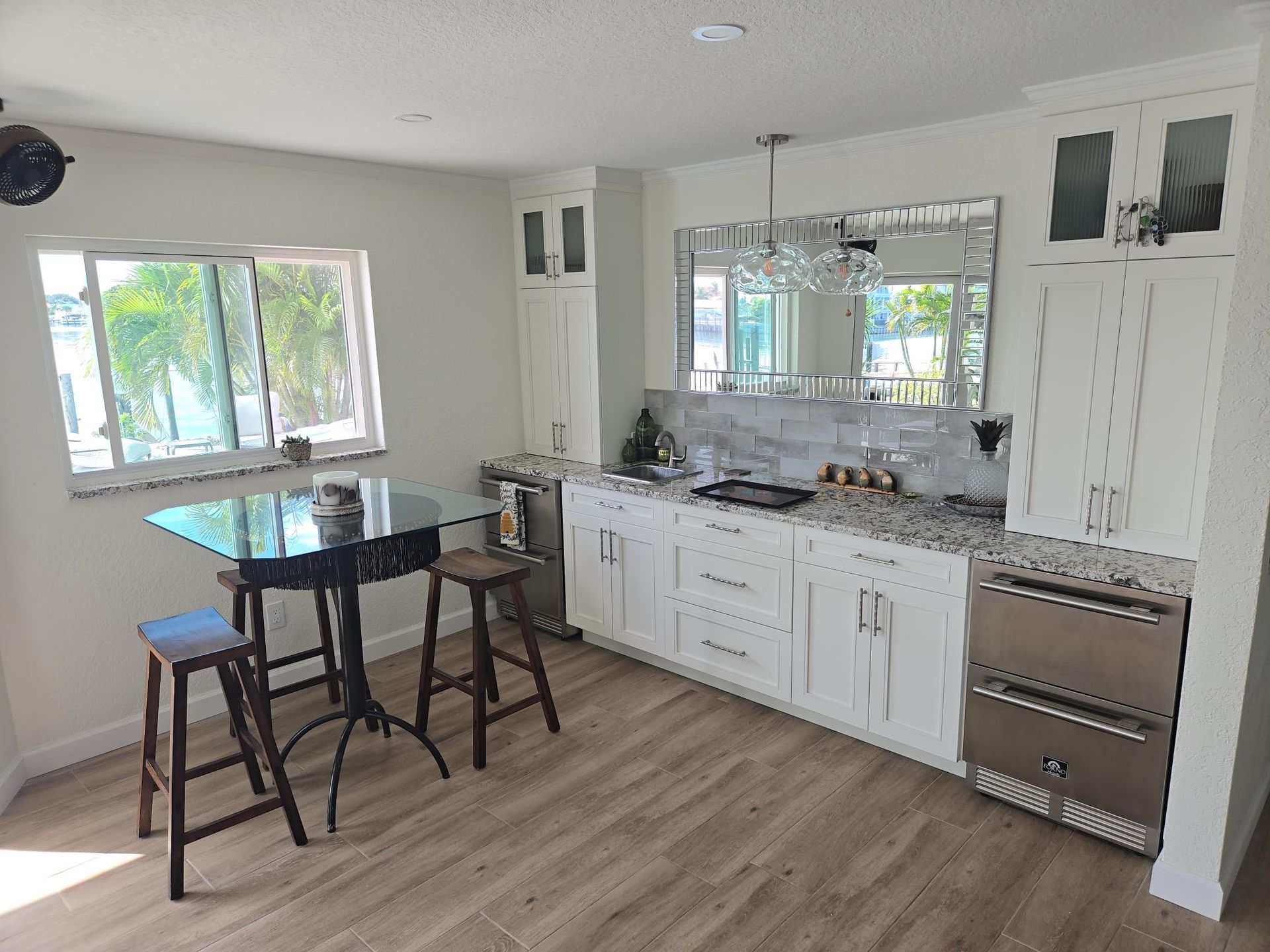 Bright modern kitchen with white cabinets, stainless stove, and a black table by the window