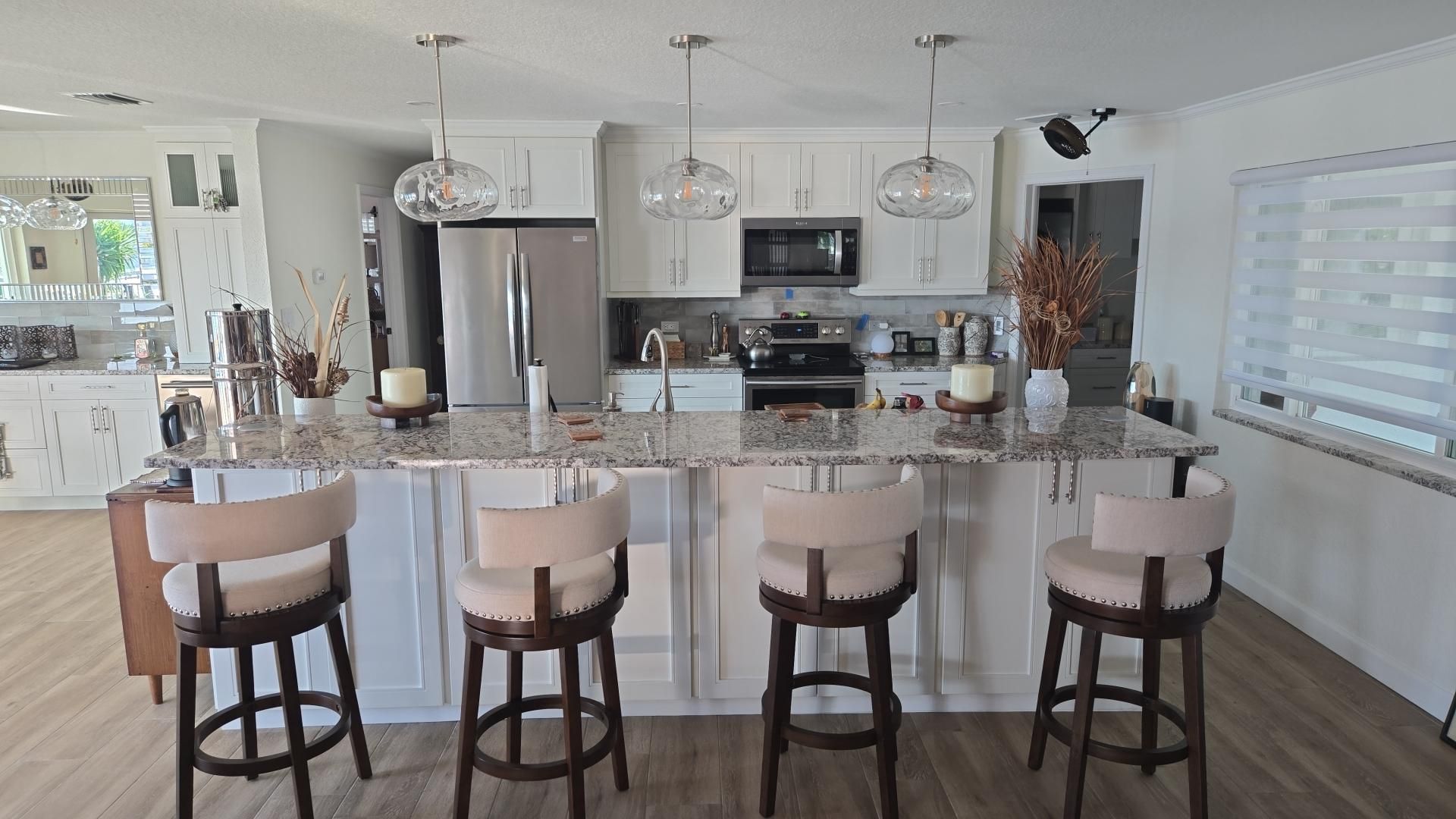Bright modern kitchen with island seating, stainless steel appliances, and white cabinets