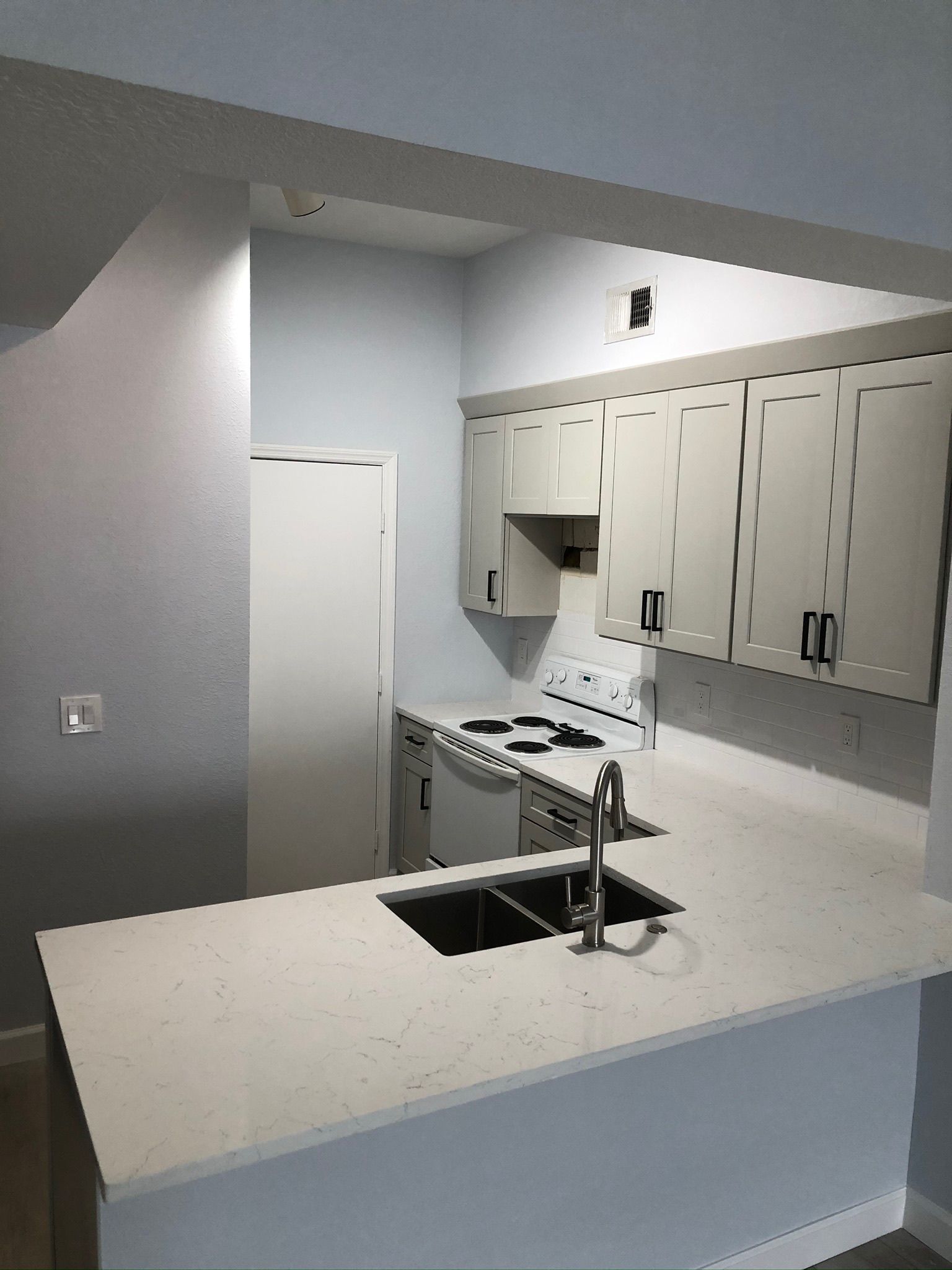 Bright kitchen with white cabinets, island, stainless stove, and a sink under a curved counter.