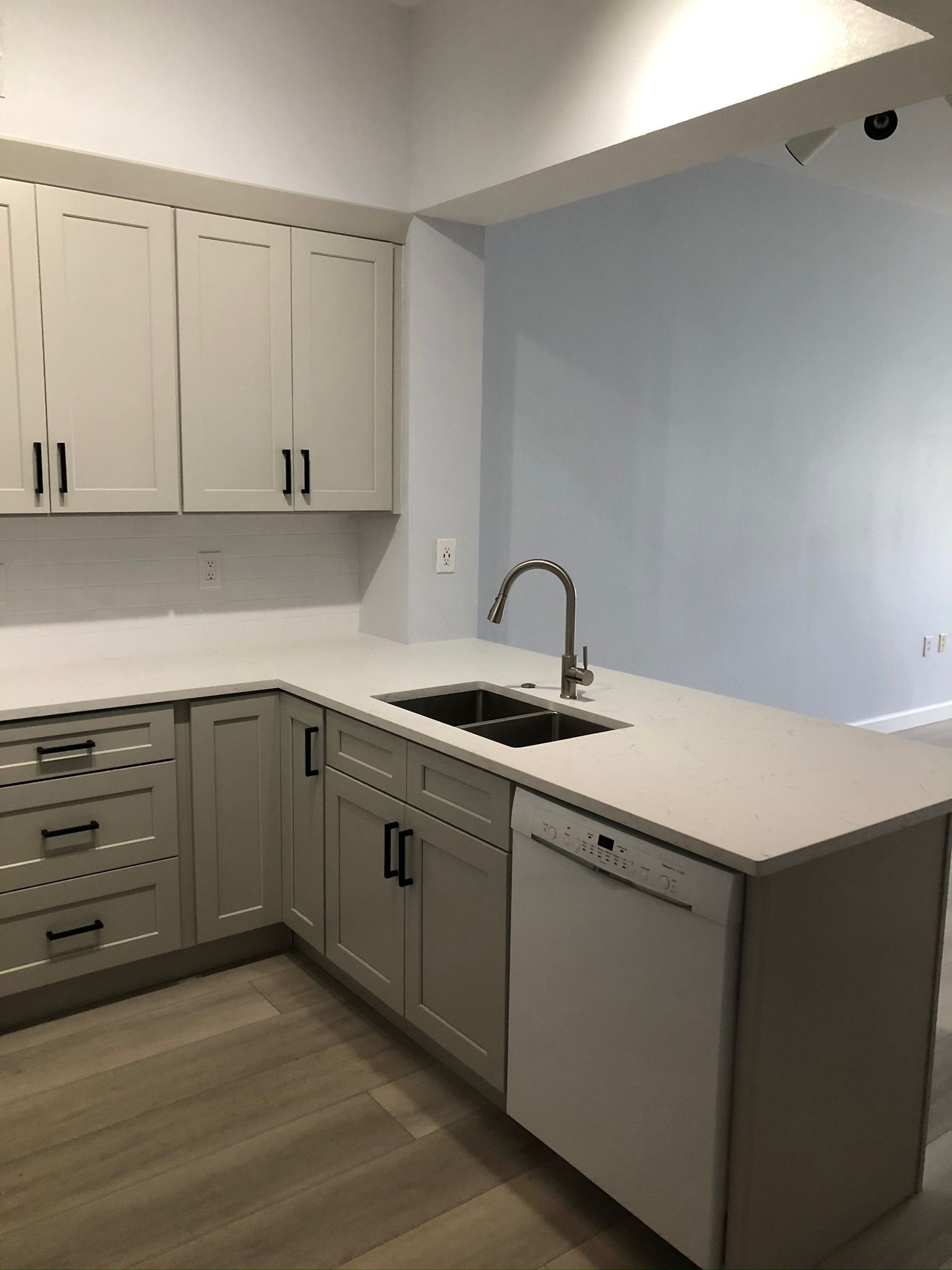 Modern kitchen with gray cabinets, white countertops, sink, and built-in dishwasher