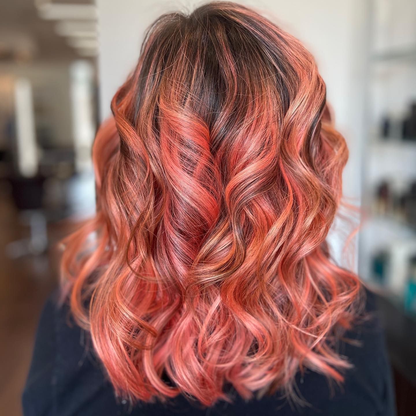Woman's hair with dark roots and ombre effect of peach and copper waves.