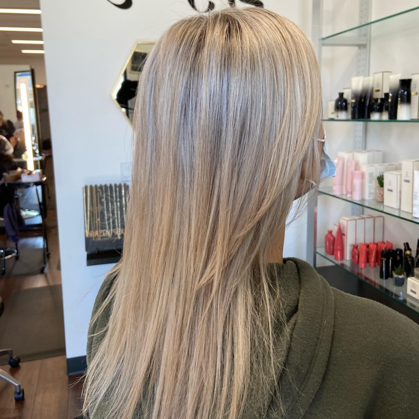 Person with blonde layered hair in a salon.
