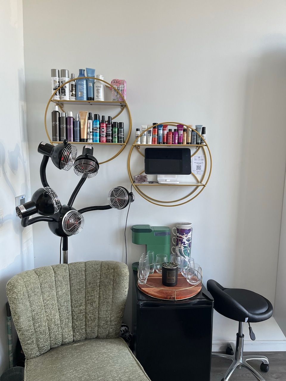 Salon station with shelves of products, hair dryer, chair, and mini-fridge.
