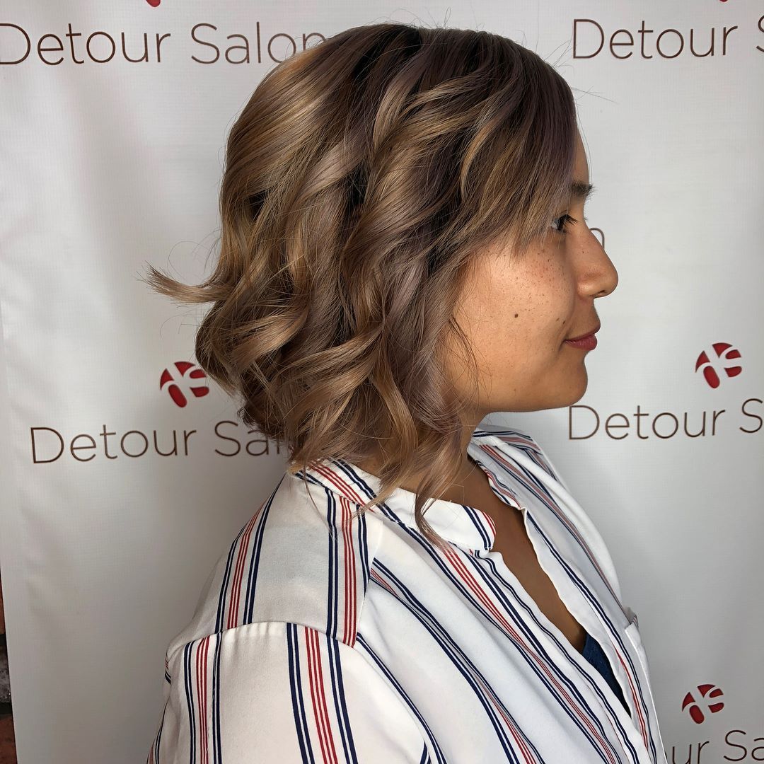 Woman with wavy brown hair, wearing striped shirt, profile view.