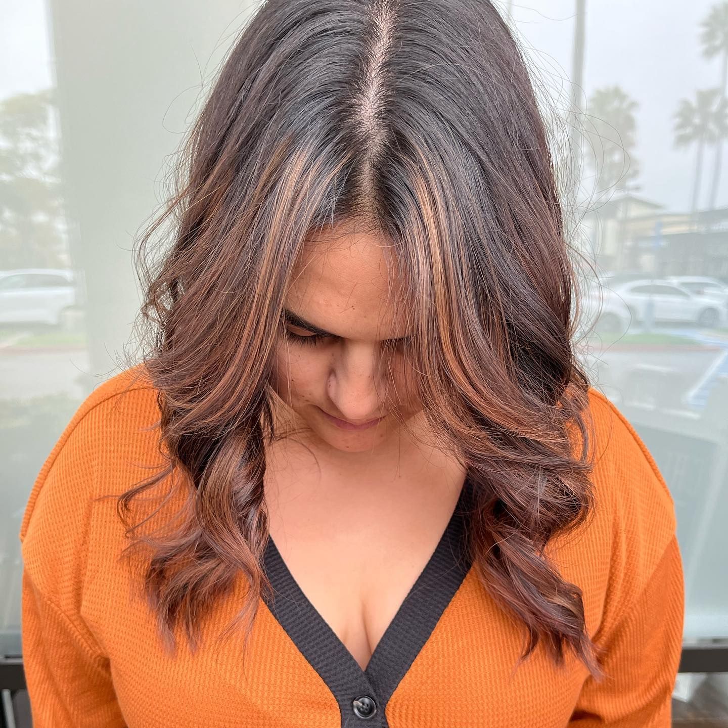 Woman with wavy brown hair, wearing a rust-colored sweater.