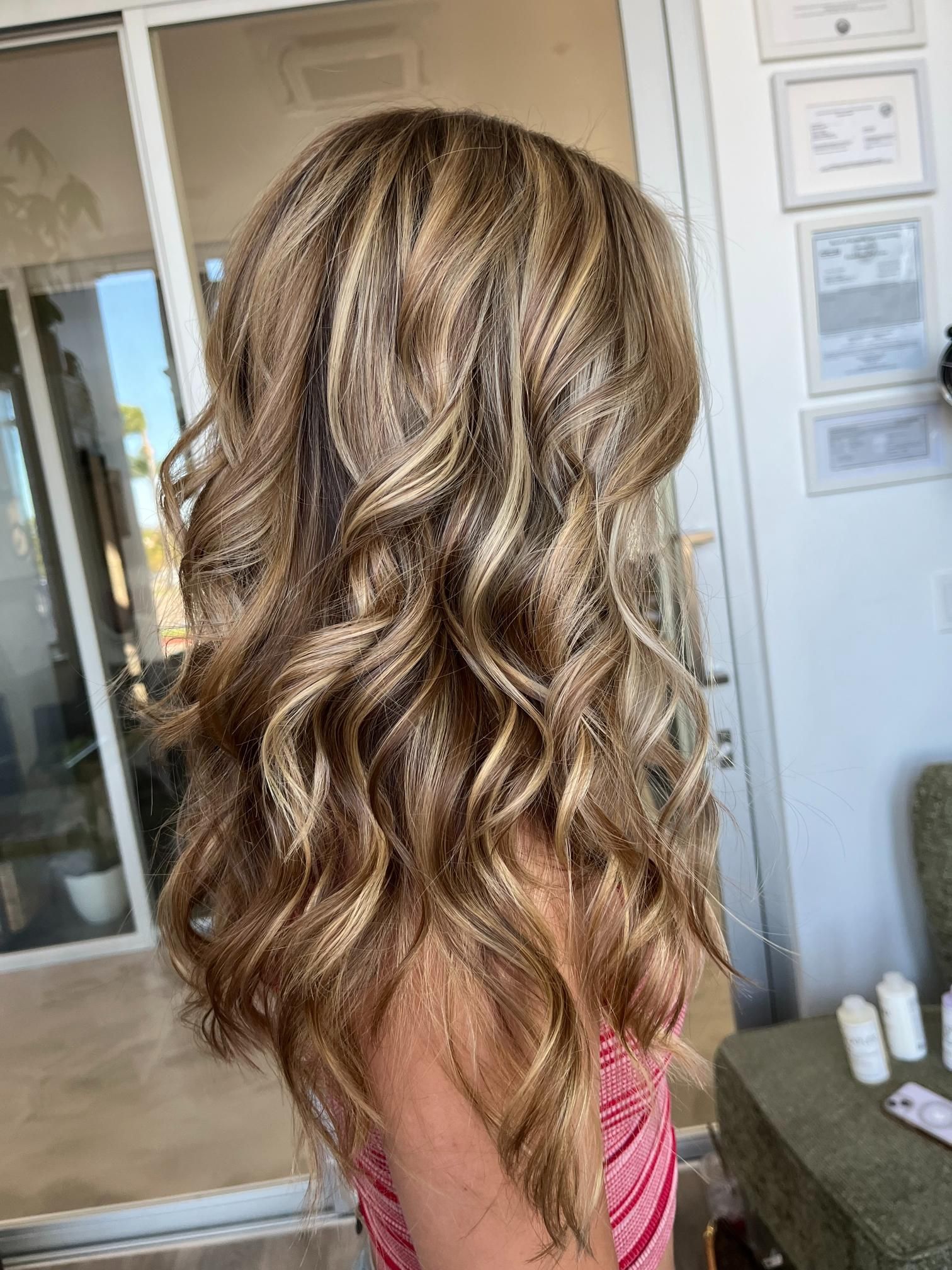 Woman's long, wavy hair with blonde highlights. Indoors, natural light.