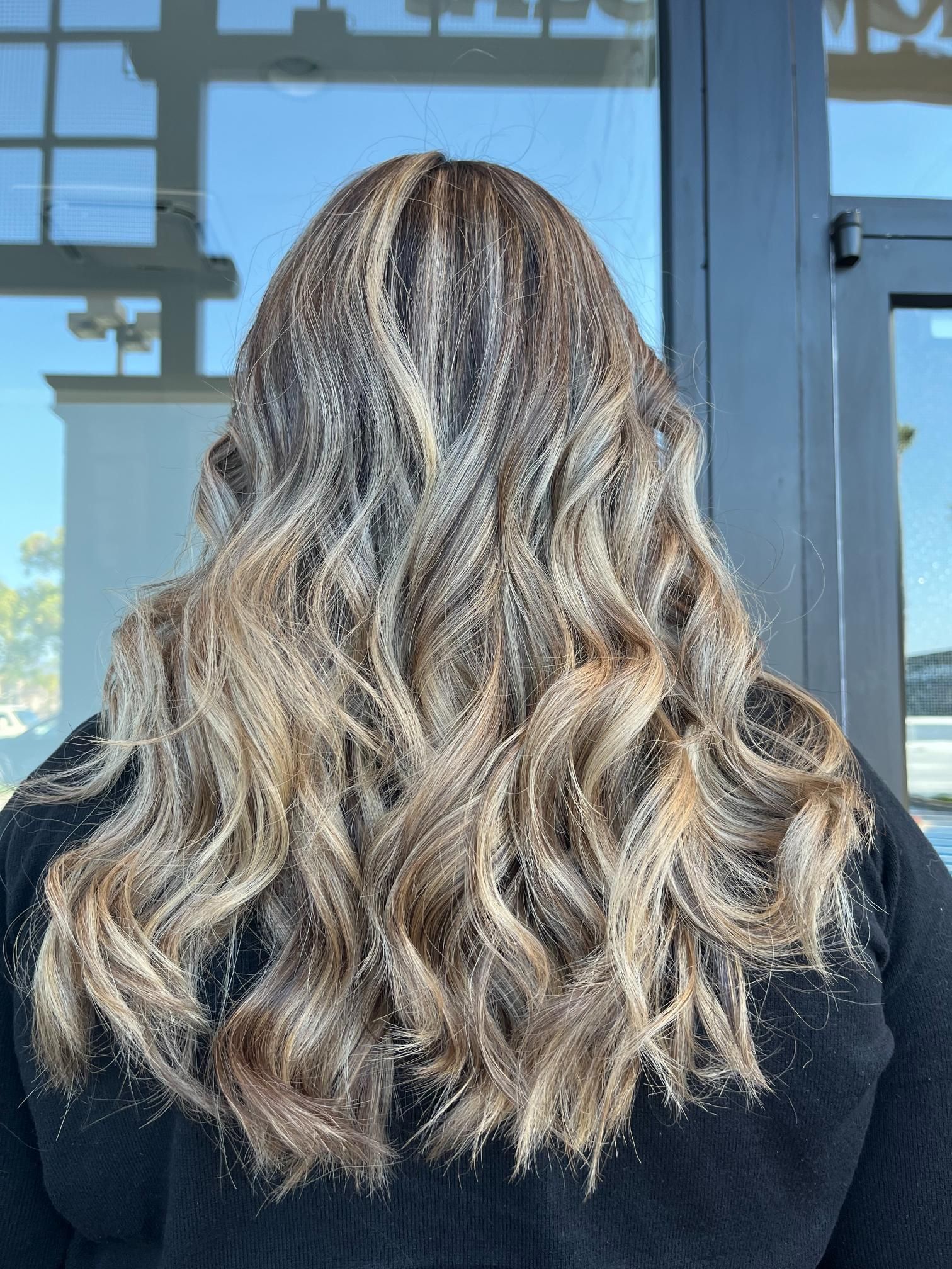 Long wavy hair, ombre, dark roots to blonde tips.