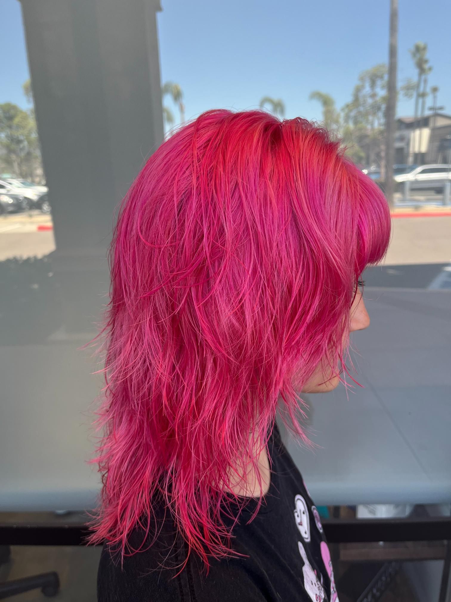 Woman with bright pink, textured hairstyle. Side view. Indoors.
