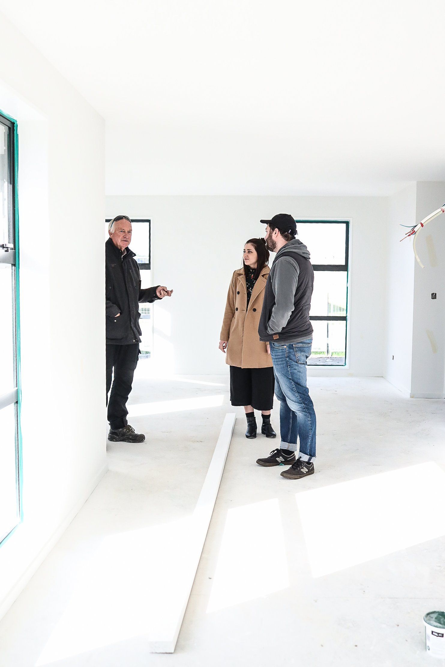 A man and a woman are standing in an empty room talking to each other.