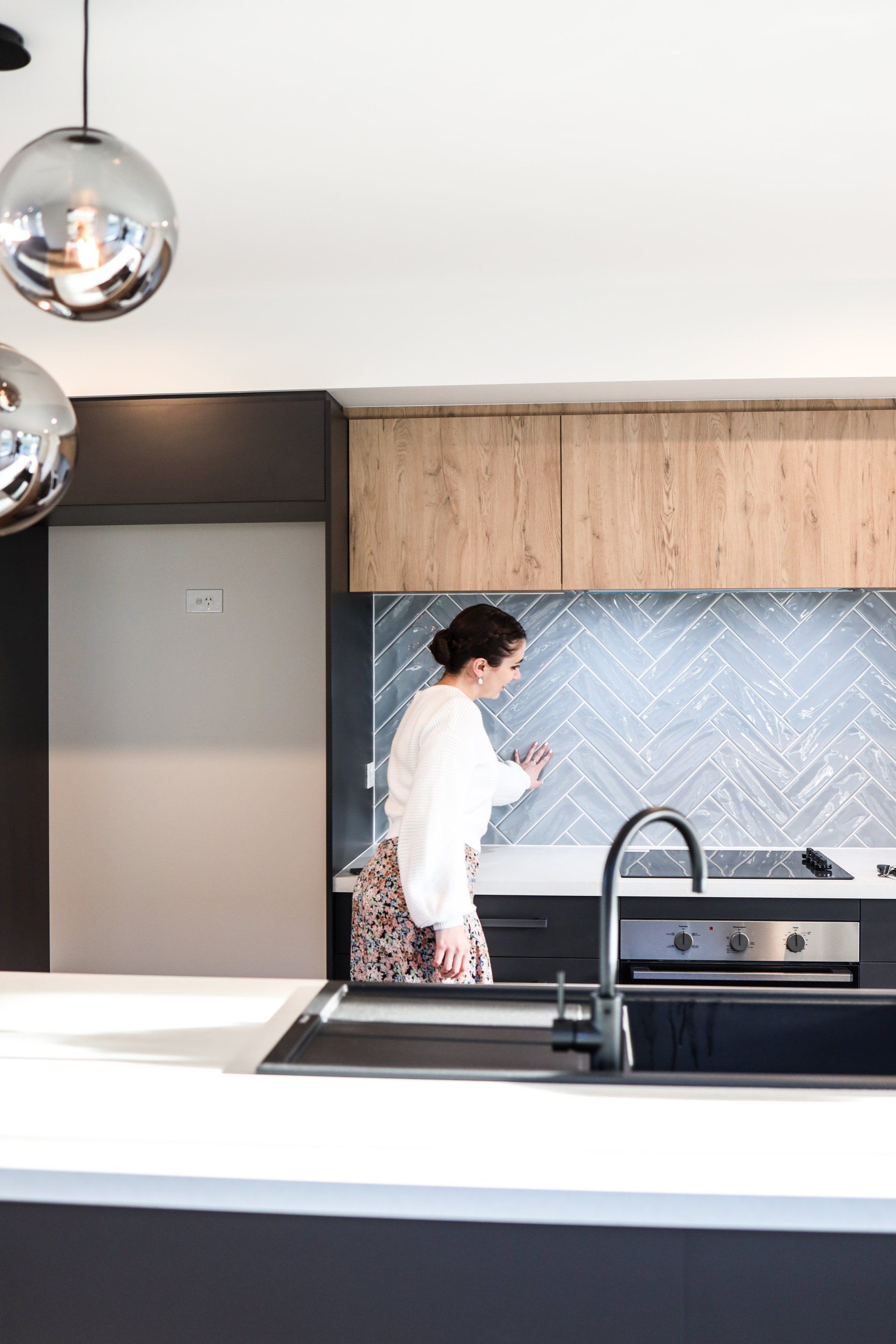 A woman is standing in a kitchen next to a sink.
