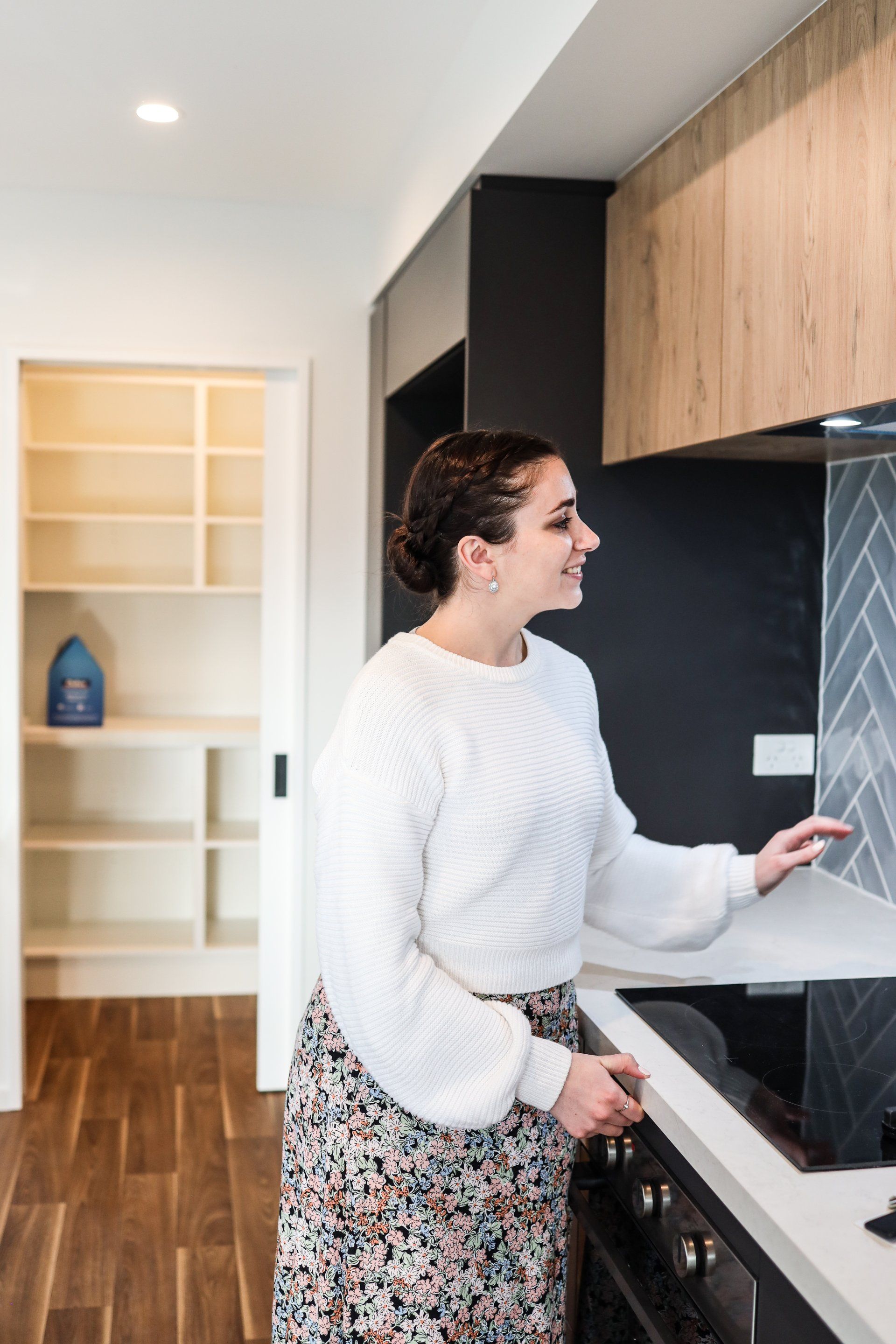 A woman is standing in a kitchen next to a stove.