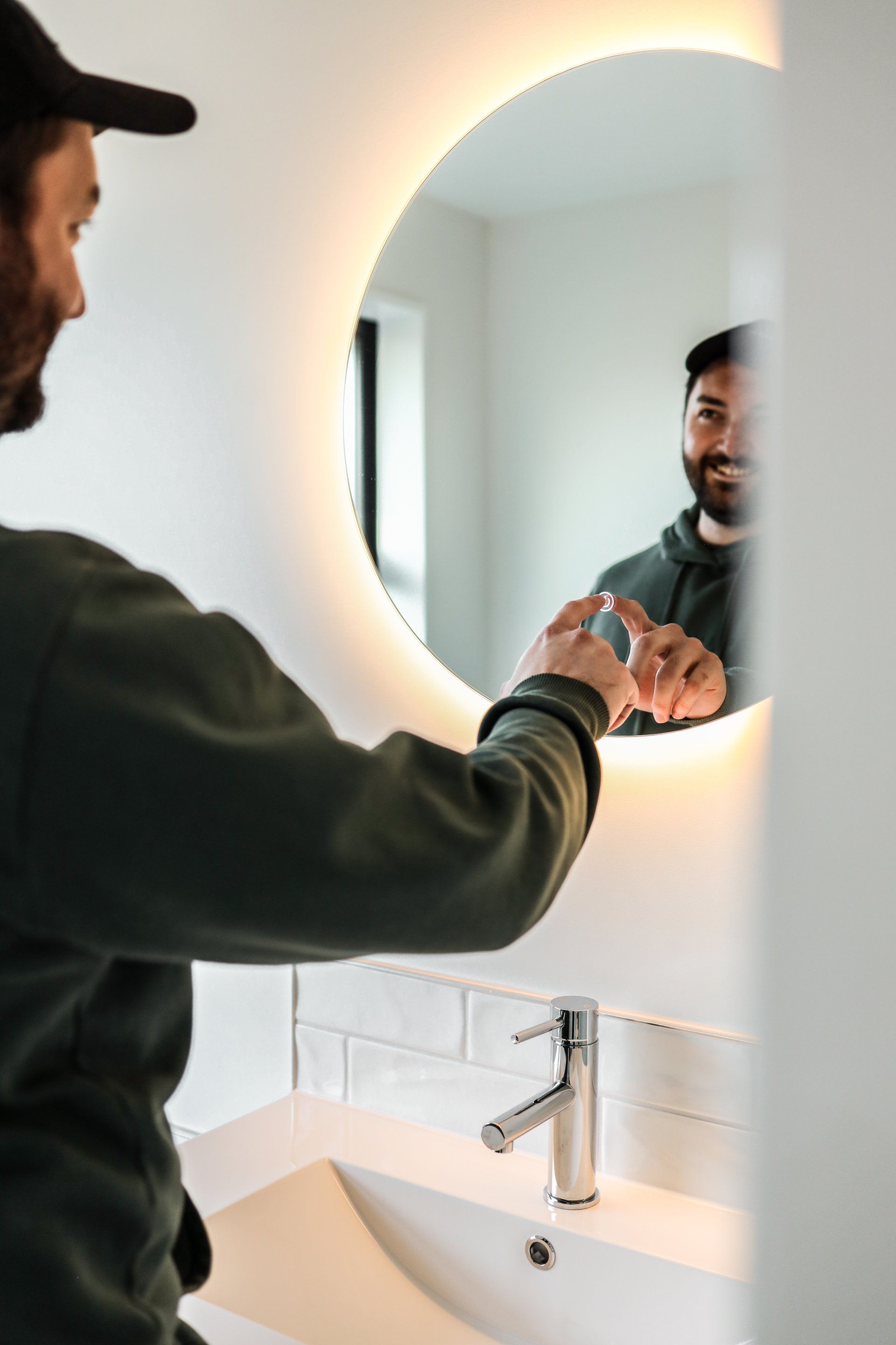 A man is looking at his reflection in a bathroom mirror.