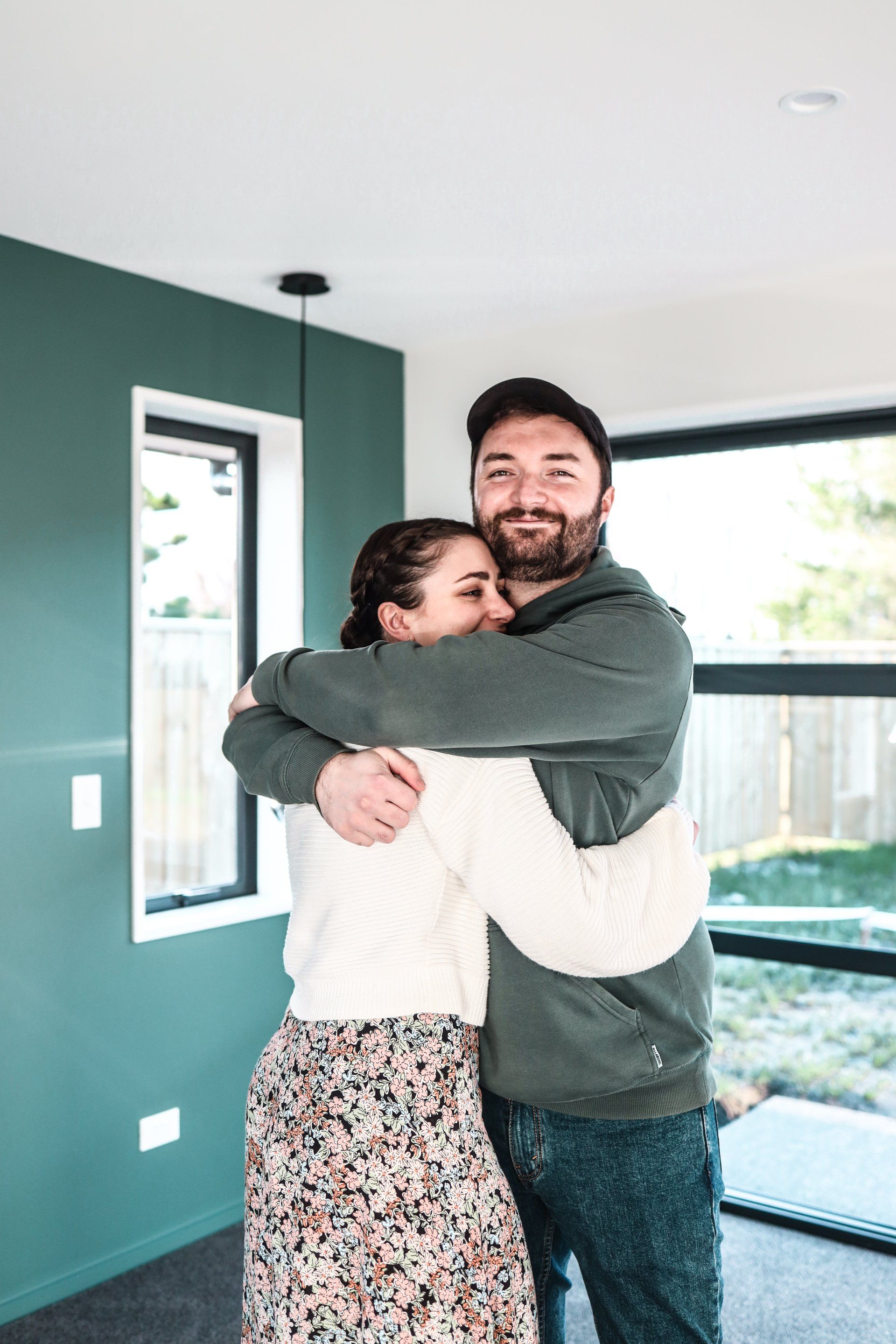 A man and a woman are hugging each other in a living room.
