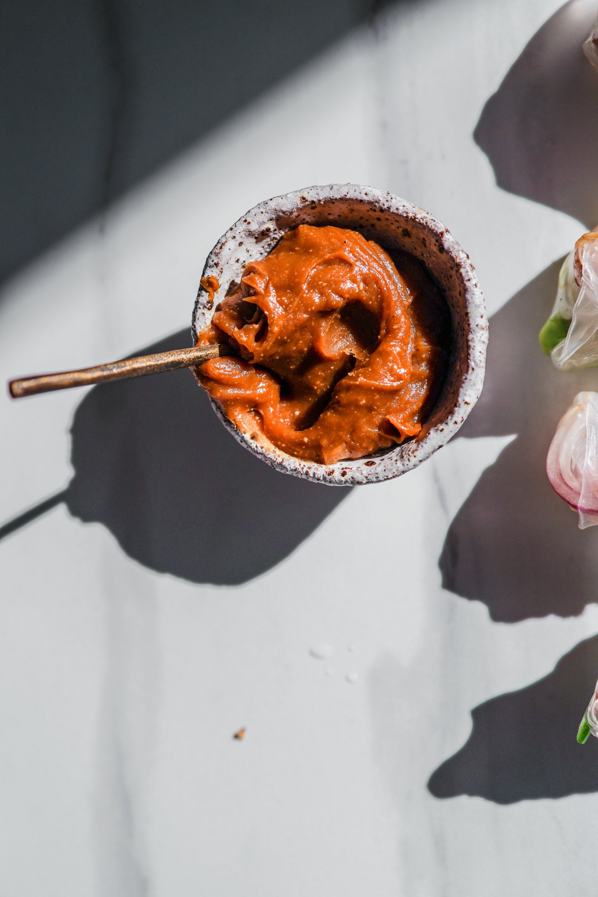 A bowl of sauce with a spoon in it on a table.