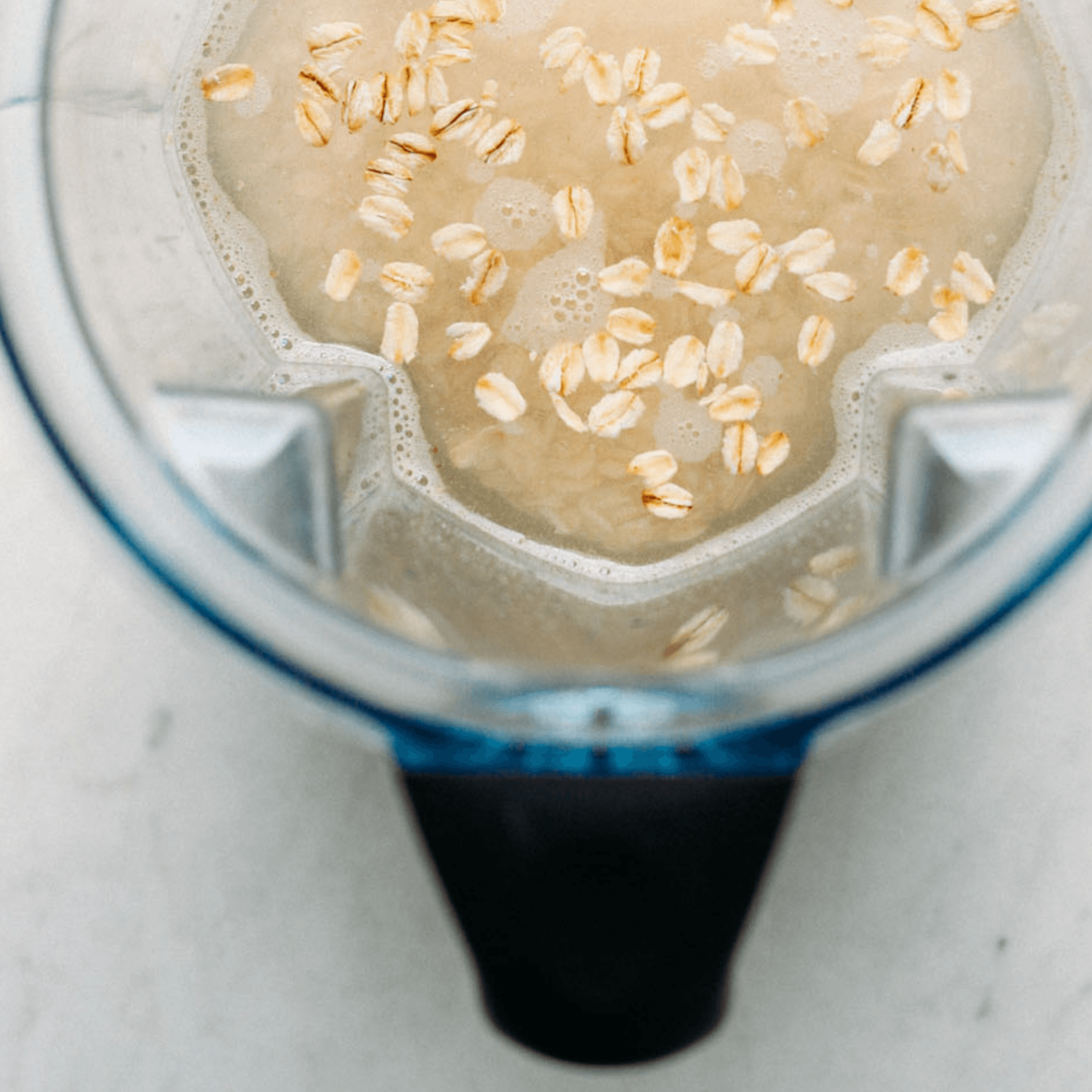 Oats are being added to a blender to make a smoothie.