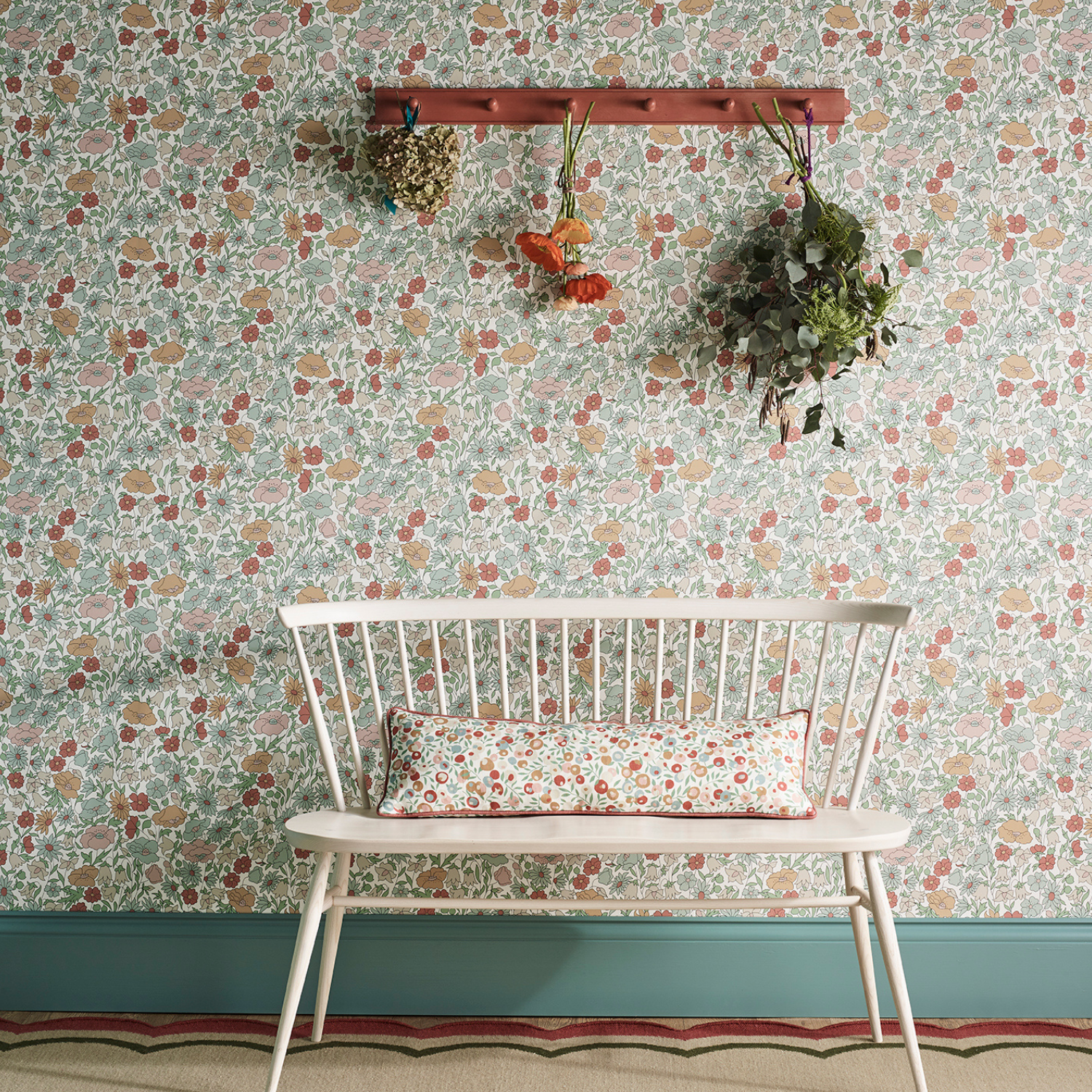 A white bench is sitting in front of a wall with a floral wallpaper.
